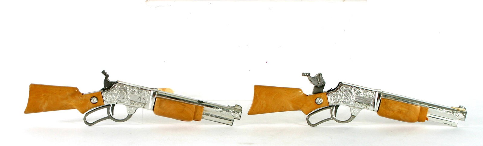 (2) NICHOLS SPIT-FIRE TOY RIFLE CAP GUNS: 1950's lever action; brown plastic and scrolled metal; both have boy's initials on side plate; L-9";
