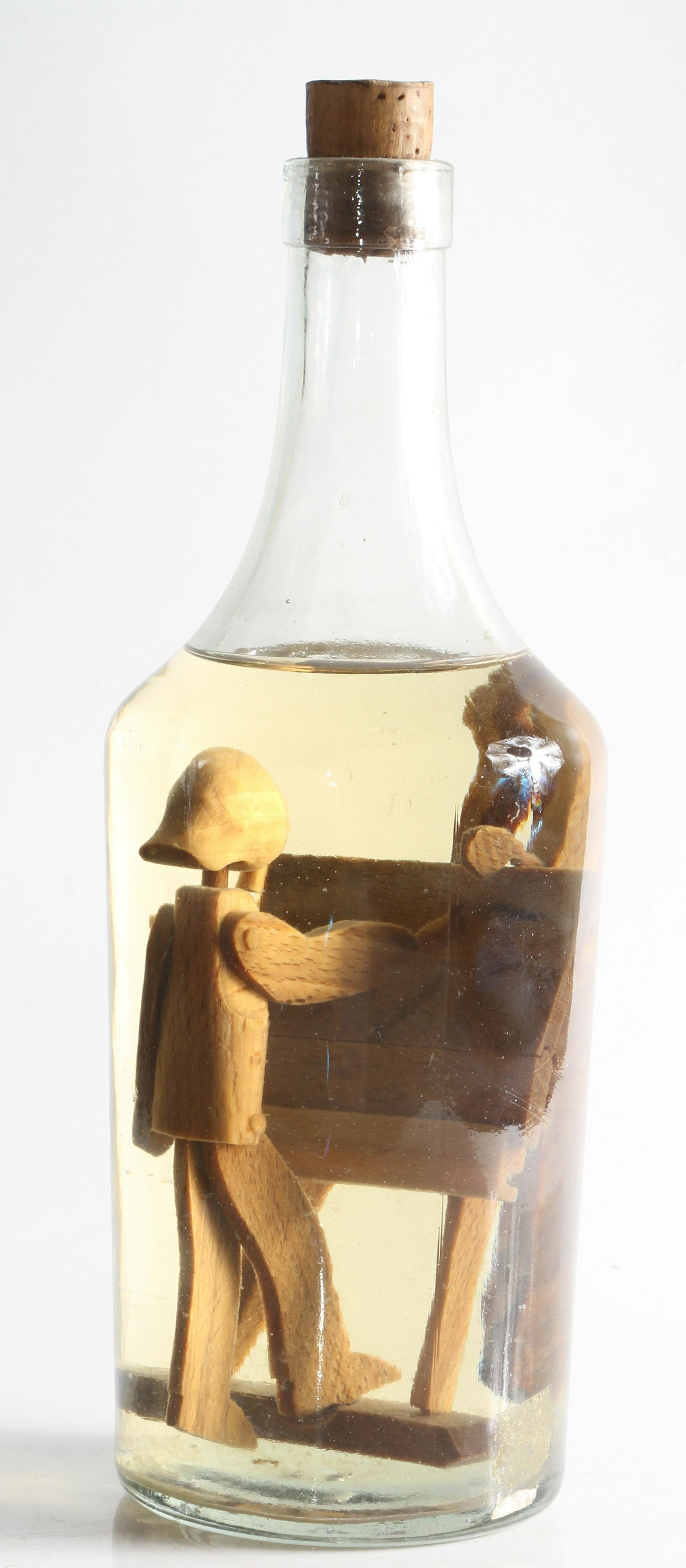 FOLK ART ARTIST IN A BOTTLE: Carved wood artist figure smoking pipe and working at an easel, mounted in water filled glass bottle, corked top; H-11", VG-EX