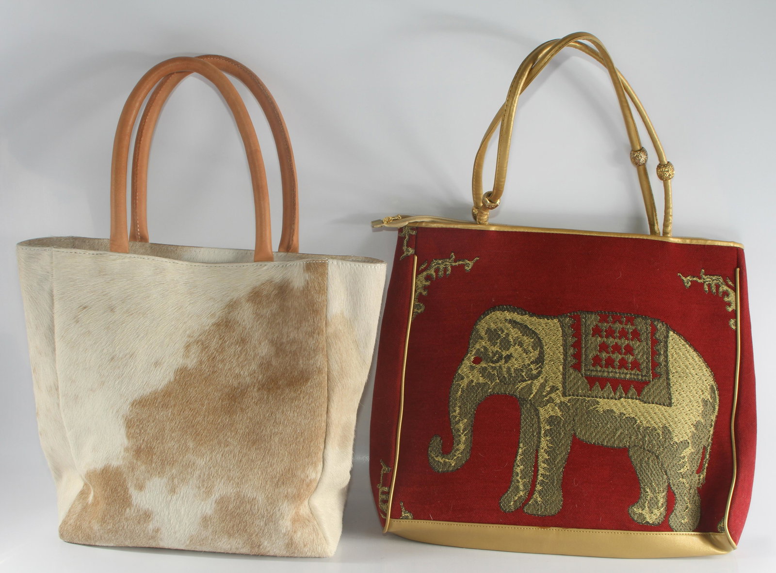 (2) TOTE STYLE BAGS: COW HIDE & ELEPHANT MOTIF: (1) large tapestry-type bag, gold leatherette handles and trim, elephant motif; black lining with zippered pockets; appears to be unused; small snag on one side; zippered closure; Made in China; 17 1/