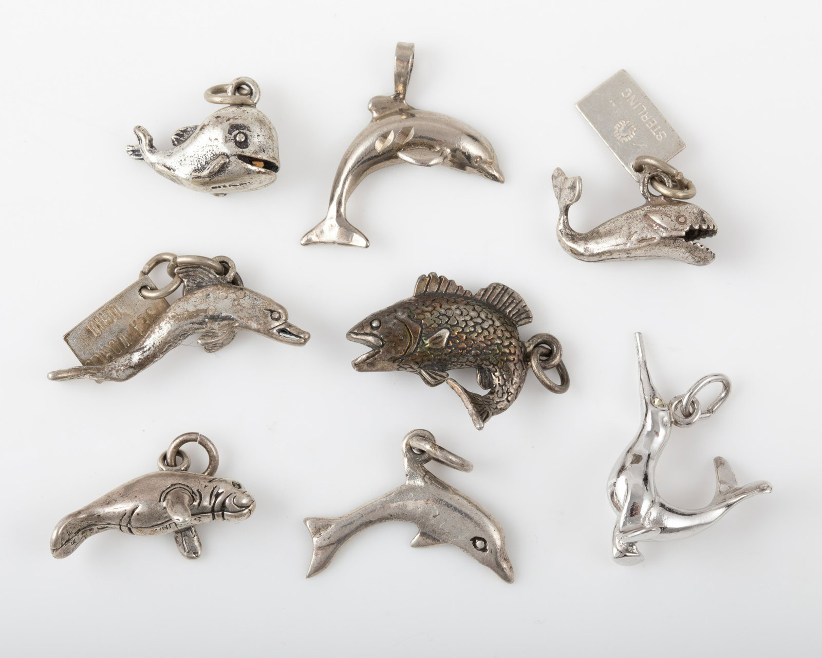 (8) SEA ANIMAL STERLING CHARMS: DOLPHINS, FISH, ETC.: Includes: (3) dolphin charms, 1-Sea World Ohio; (2) whale type charms, 1- Sea World, (1) manatee, (1) long nosed dolphin, (1) fish; [.81 ozt total], sizes 5/8" - 1 1/8", VG