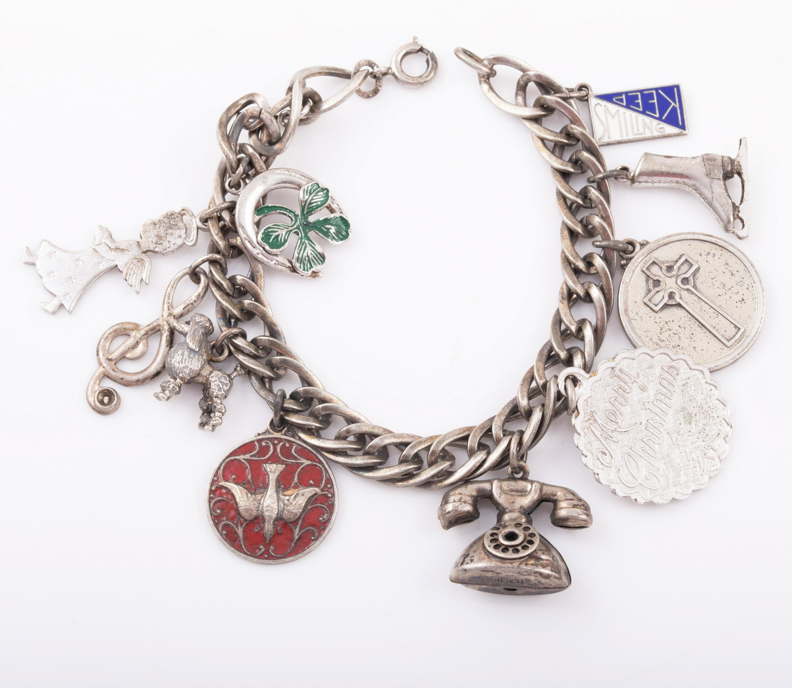 VINTAGE STERLING CHARM BRACELET: Includes: enameled Sweet 16 charm, poodle, treble clef, angel, telephone, ice skate, horseshoe & clover with enamel, enameled Keep Smiling, "Merry Christmas", "I'm a Presbyterian"; chain is inter-lock