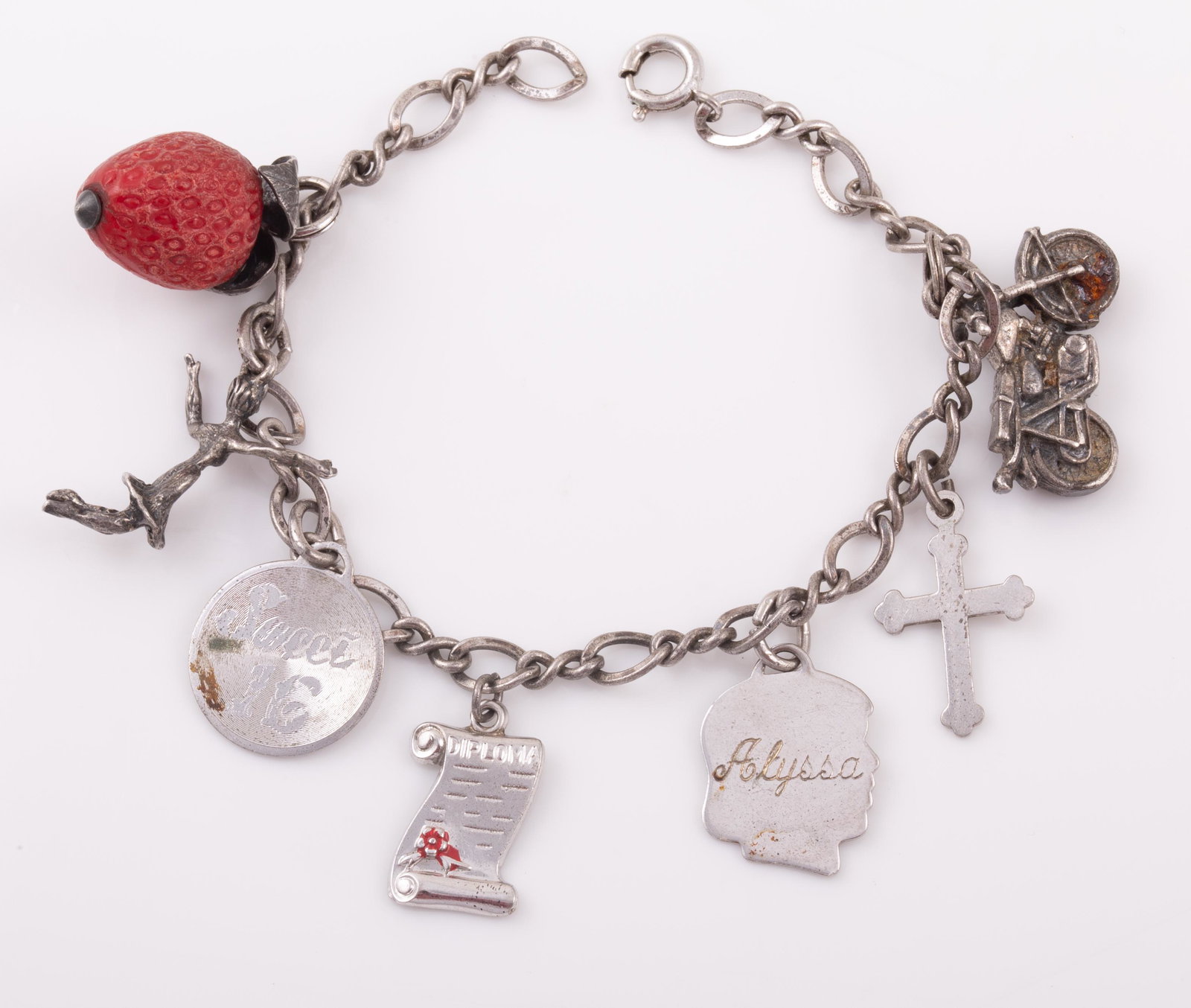 VINTAGE STERLING CHARM BRACELET: includes: sterling & plastic strawberry, sweet 16, cross, motorcycle, engraved silhouette, diploma, dancing girl; L-6 1/2", .63 ozt total; G-VG