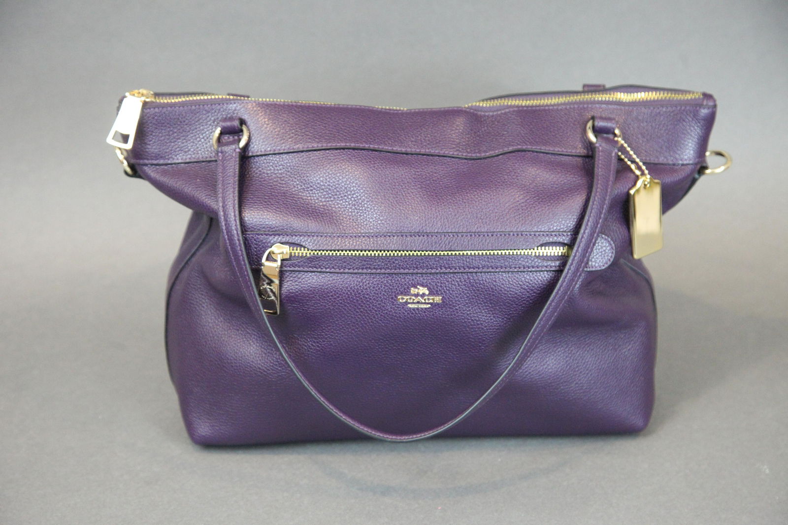 COACH AUBERGINE TYLER TOTE: Pebbled leather; (2) interior open pockets, (1) interior zipper pocket, exterior zipper pocket; retains cross body strap; brass hang tag; retains original price tag with bar code; L-19 1/2" including