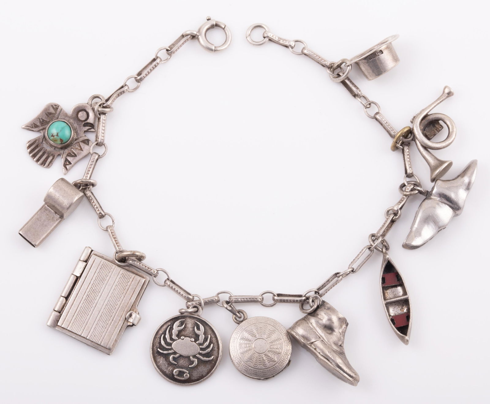 STERLING CHARM BRACELET: 10 CHARMS: hat, horn, winged foot. canoe, boot, compact, cancer symbol, book, whistle + s.w. bird with turquoise; book and compact are hinged; .48 ozt total, L - 7" G - VG .