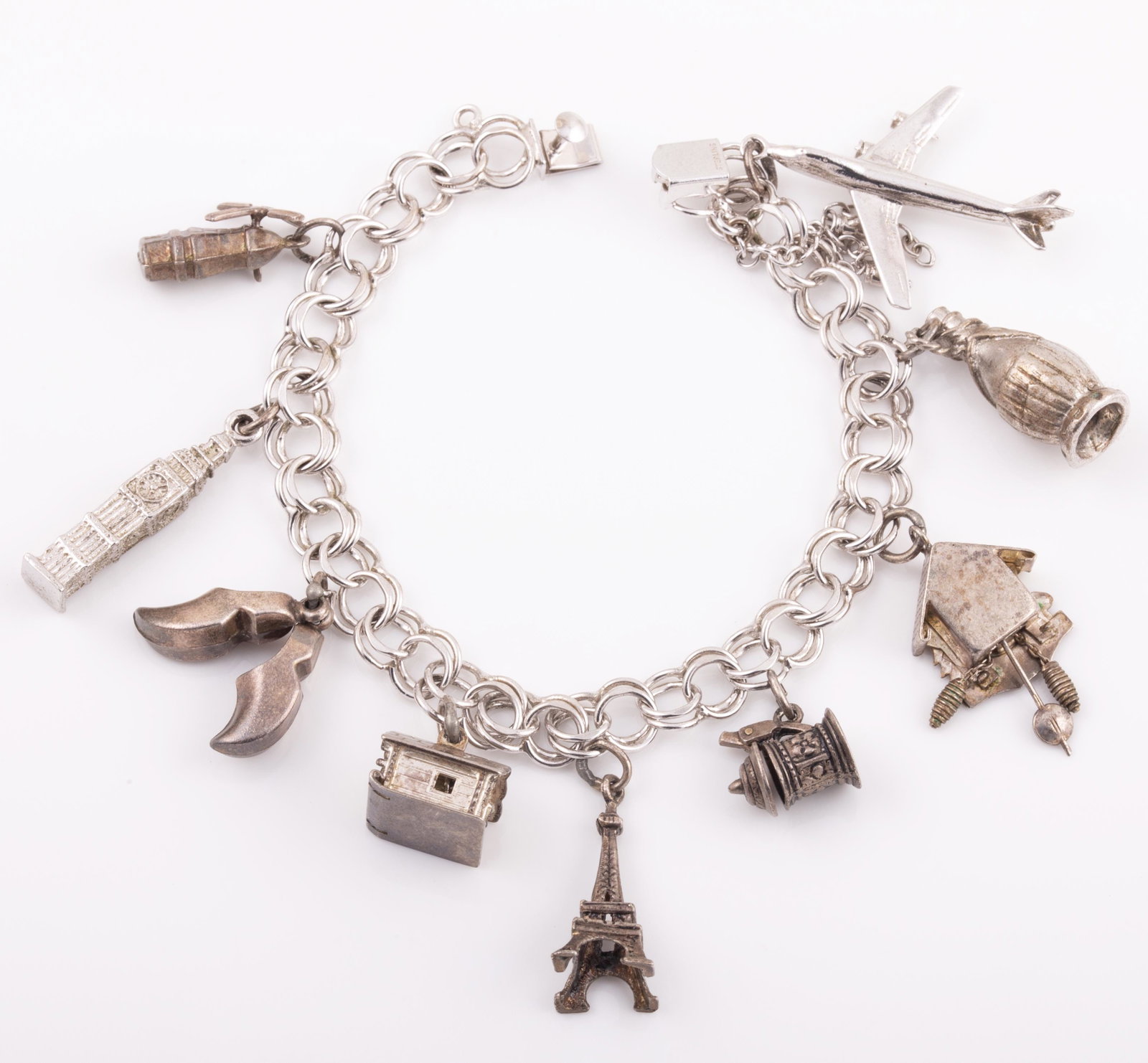 STERLING CHARM BRACELET: 9 travel charms: airplanes, wine bottle, cuckoo clock, stein, eiffel tower, log cabin, dutch shoes, clock tower & windmill; 1. ozt L - 7", G -VG