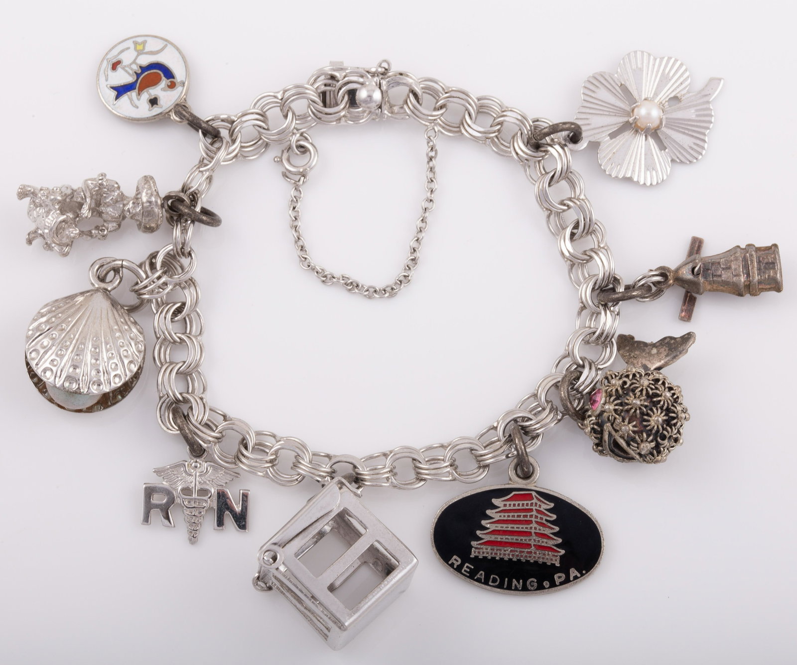 STERLING CHARM BRACELET: 9 Charms: clam shell, R.N., drummer, mad money box, fish, windmill, clover, etc.; .98 ozt L - 7 1/2" G - VG