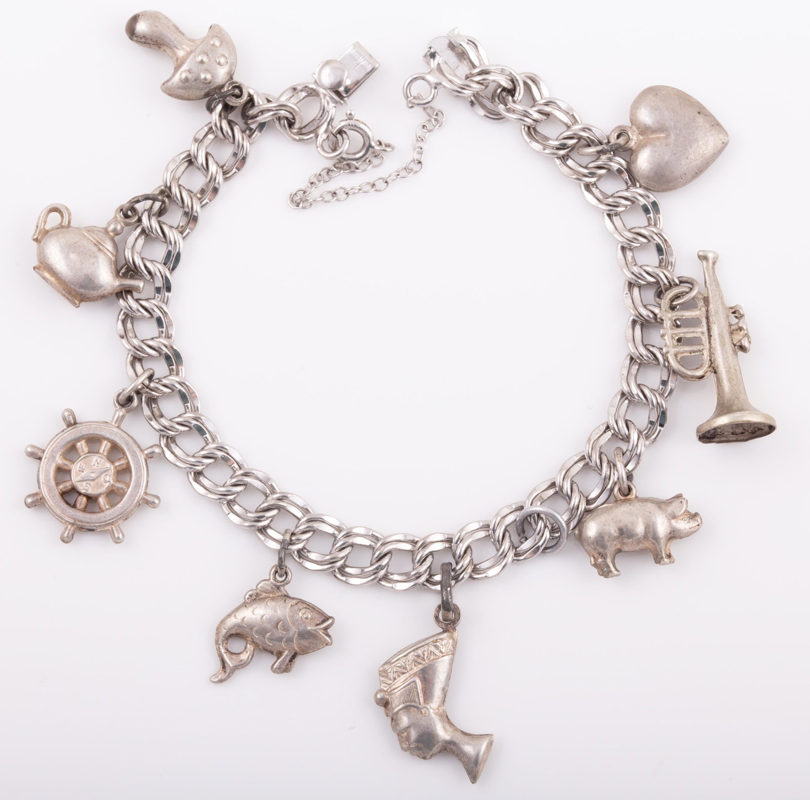 STERLING CHARM BRACELET: 8 Charms: Nefertiti, trumpet, heart, pig, mushroom, teapot, ship's wheel, fish; .58 ozt L - 7 1/4" VG- EX