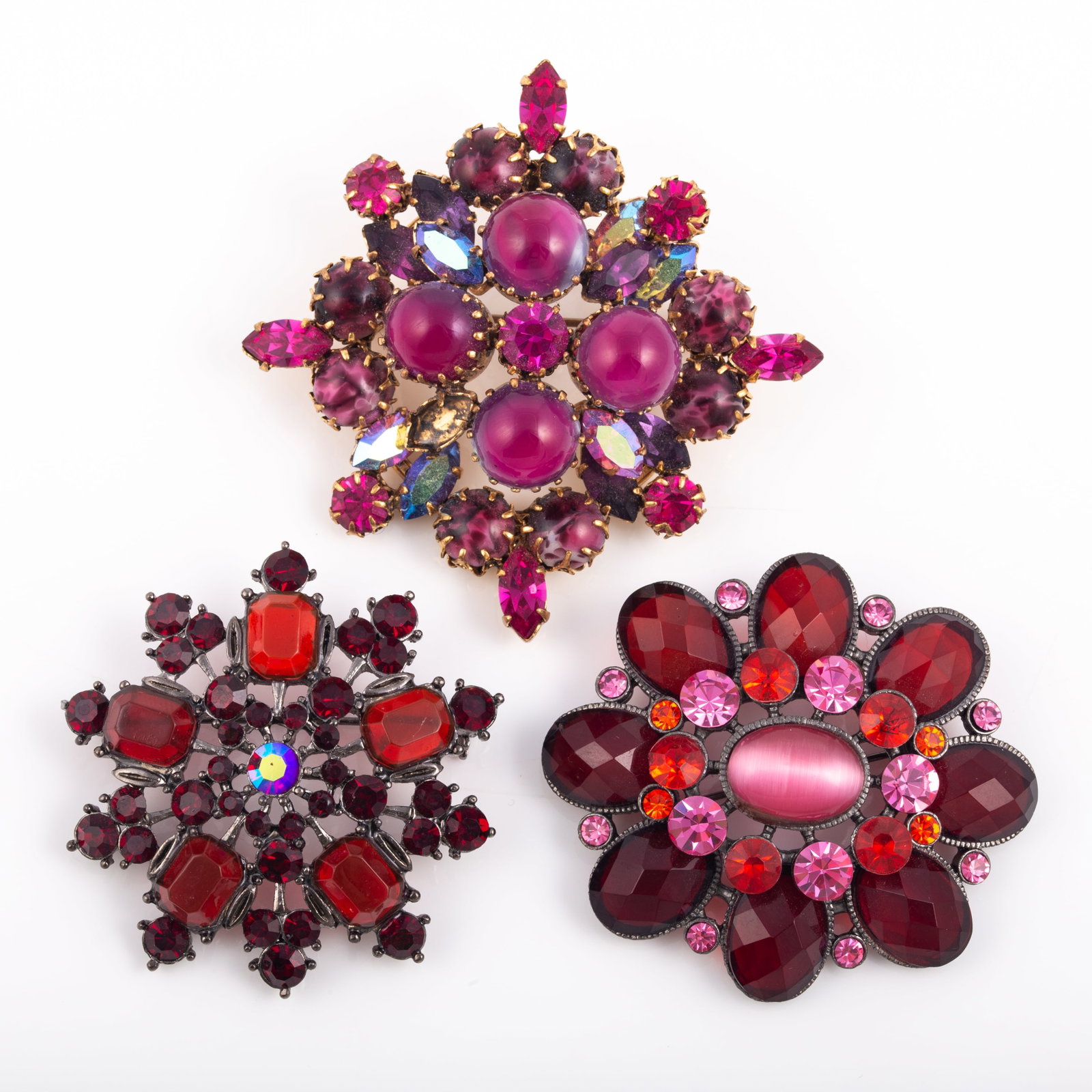 (3) RED VINTAGE RHINESTONE BROOCHES: Includes: (1) Made in Austria, prong set pink rhinestone brooch, featuring opaque cabochon, AB and faceted stones, (1) marquise AB stone missing; gold tone backing; (1) gun metal tone brooch featuring