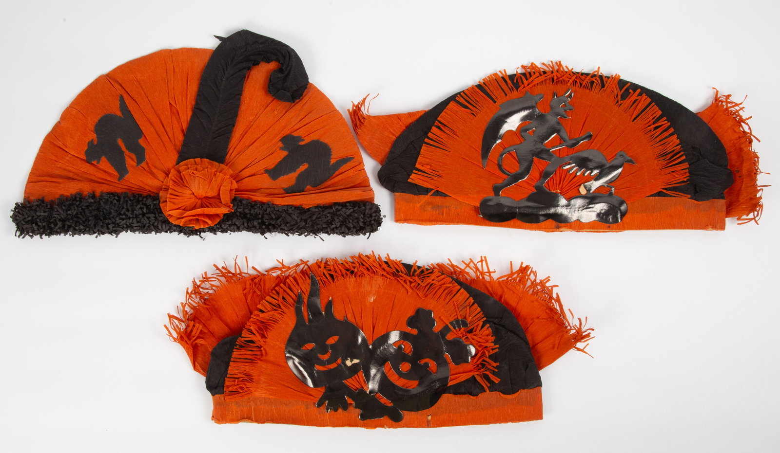 (3) VINTAGE GERMAN HALLOWEEN HATS: Crepe paper and die-cut cardboard; (1) all crepe paper with black cats; (1) crepe paper with die-cut devil chasing a crow; (1) crepe paper with die-cut jack o'lanterns; very fragile, condition is over