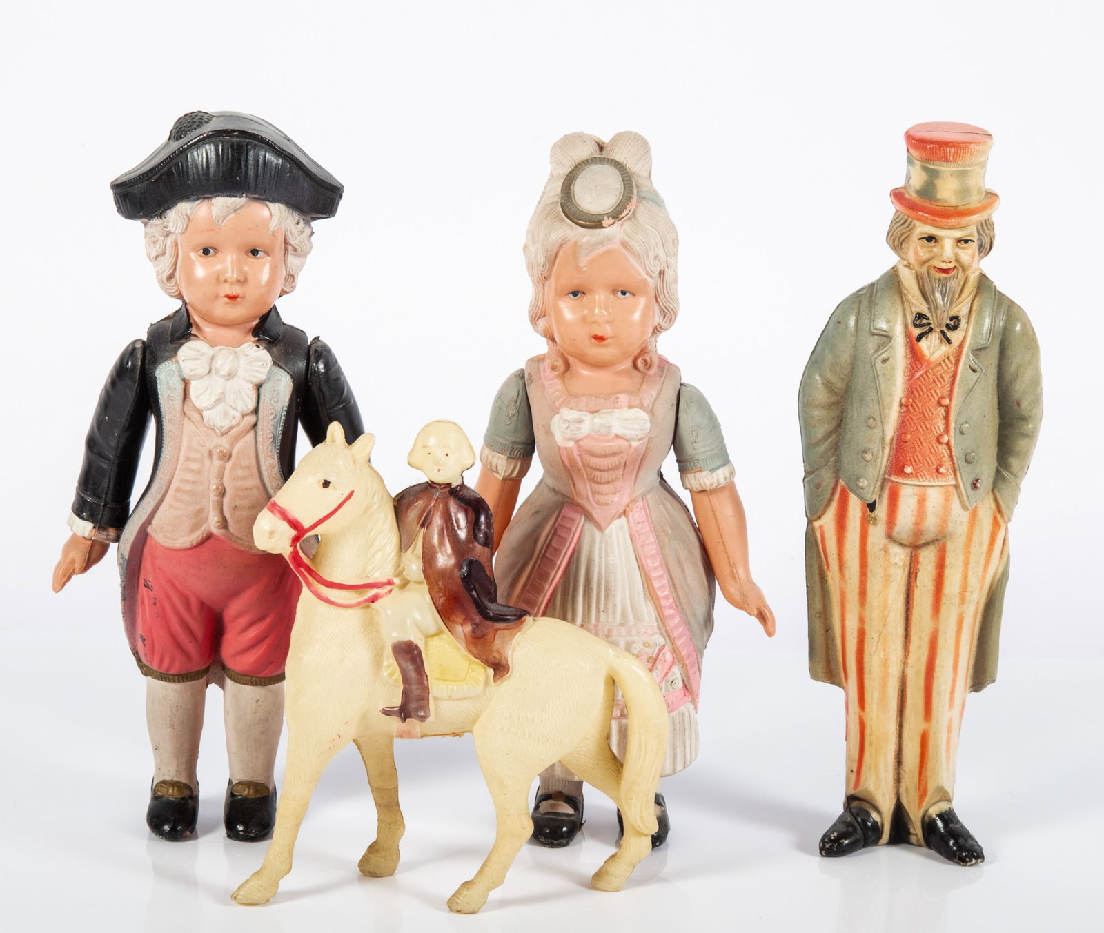 (4) PATRIOTIC CELLULOID FIGURES - JAPANESE & AMERICAN: (1) George Washington on horseback; some fading; celluloid is very clean, L-5"; (2) figures, George and Martha Washington, jointed arms; colonial costumes; both marked with cross in circle; H-7 1/4"; 
