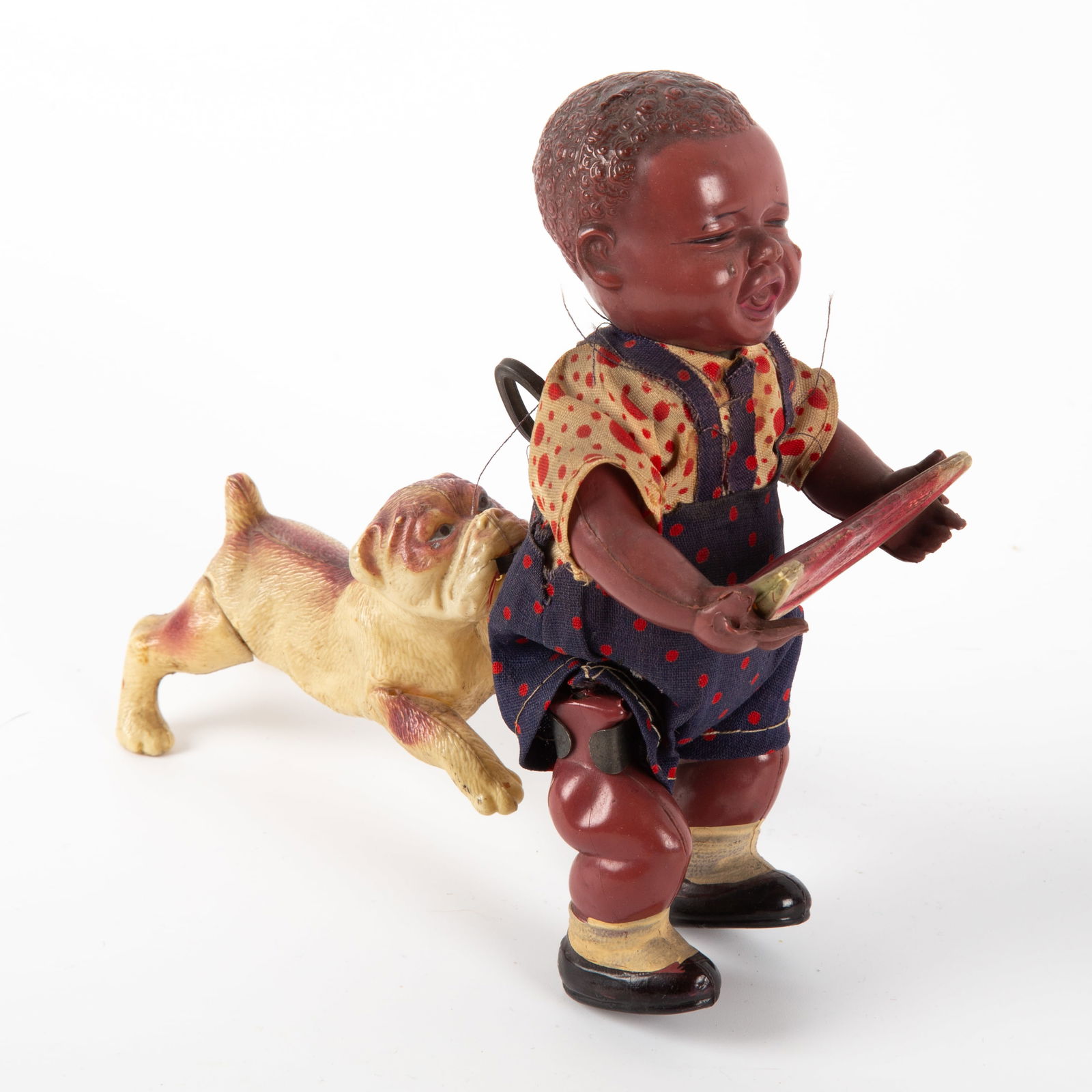 "POOR PETE" CELLULOID JAPAN WIND-UP: Black boy eating watermelon with bulldog biting his derriere; cloth dressed celluloid figure, celluloid dog; clockwork mechanism works well; fabric clothing shows minor wear, staining and age; cellulo
