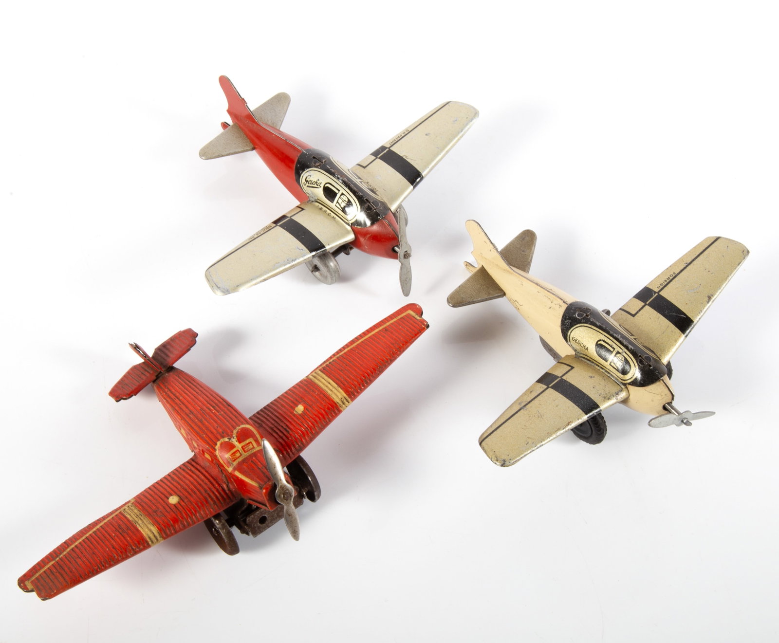 (3) GERMAN WIND-UP AIRPLANES - GESCHA, ETC.: (1) German tin airplane, ribbed finish, wind-up mechanism works, wheels turn and propeller spins; mechanism has significant oxidation; mechanism is missing a pin to hold it away from the wings; marked