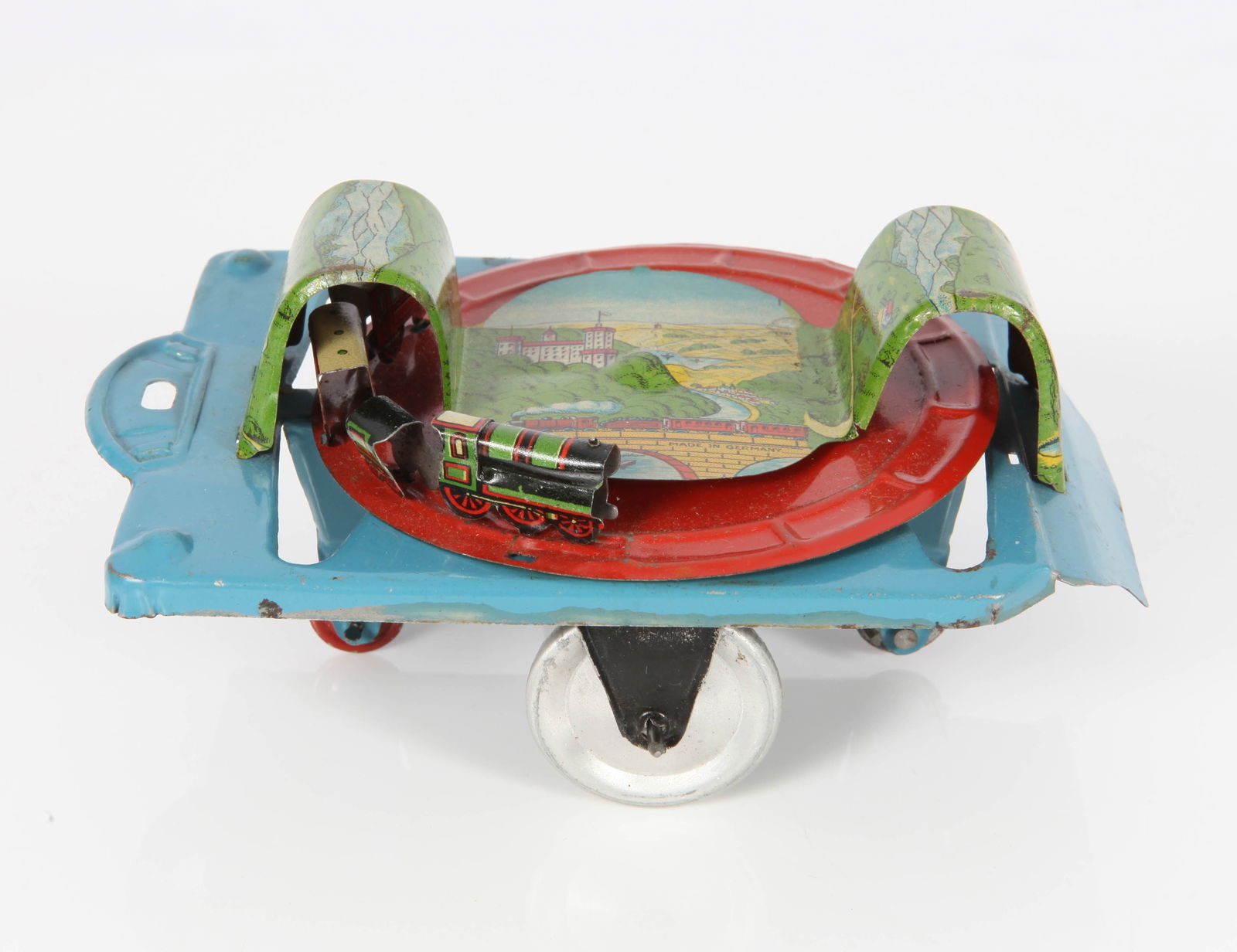 GELY / GEORGE LEVY GERMAN TIN TRAIN PLATFORM TOY: Litho tin; gear driven pull toy; as wheels roll the tin train runs around the track through the tunnels; very clean with minimal blemishes; marked "Made in Germany"; L-5 34"'