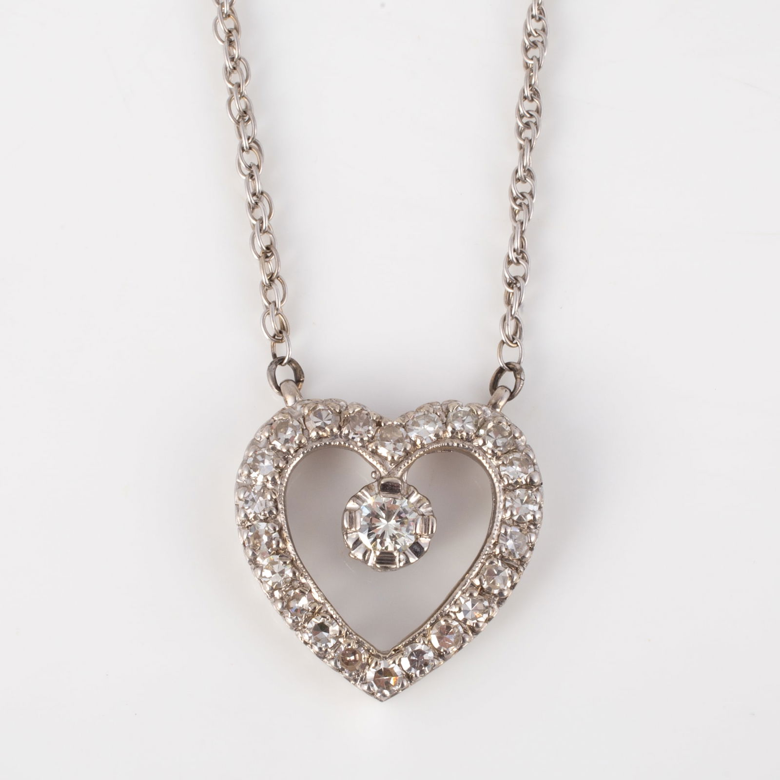 14K WHITE GOLD NECKLACE WITH DIAMOND HEART DROP: Fine white gold chain, marked 14K Sylkay; terminating in white gold heart pendant set with (22) .03 carat +/- round diamonds and (1) .15 carat +/- round central diamond; L-20", [4.5 dwt total]