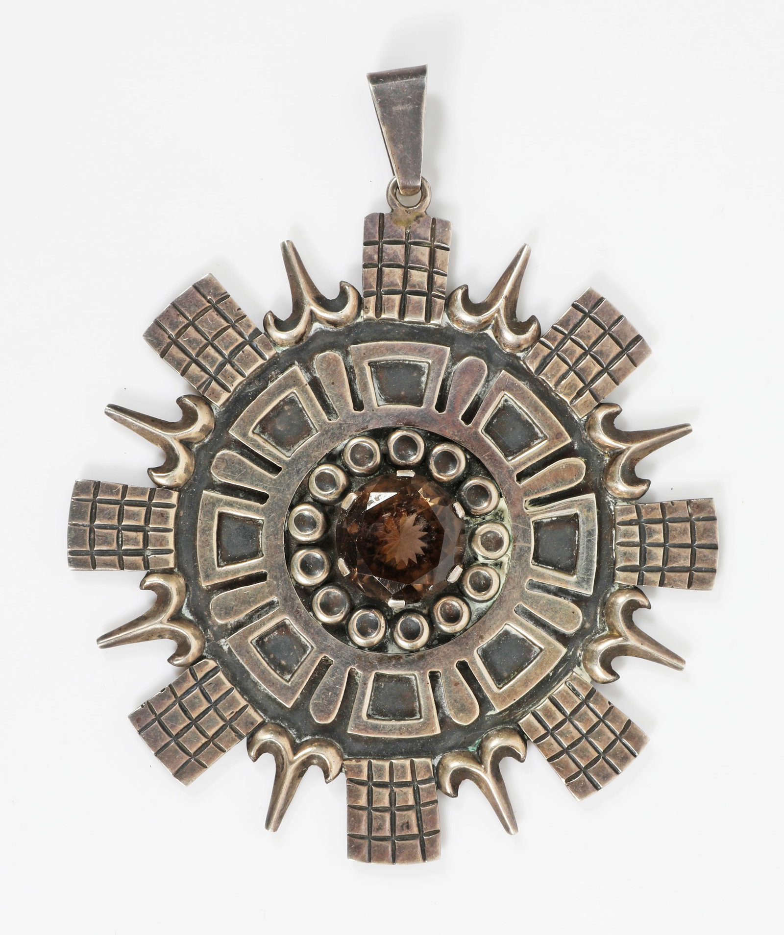 NESTOR MEXICAN SILVER SMOKEY QUARTZ PENDANT: Aztec inspired design with central faceted smokey quartz stone (approx. 15.5mm dia.), 3 eagle mark, appears to be stamped "Hecho en Taxco Nestor", also stamped 925 and sterling; reverse has some adhes