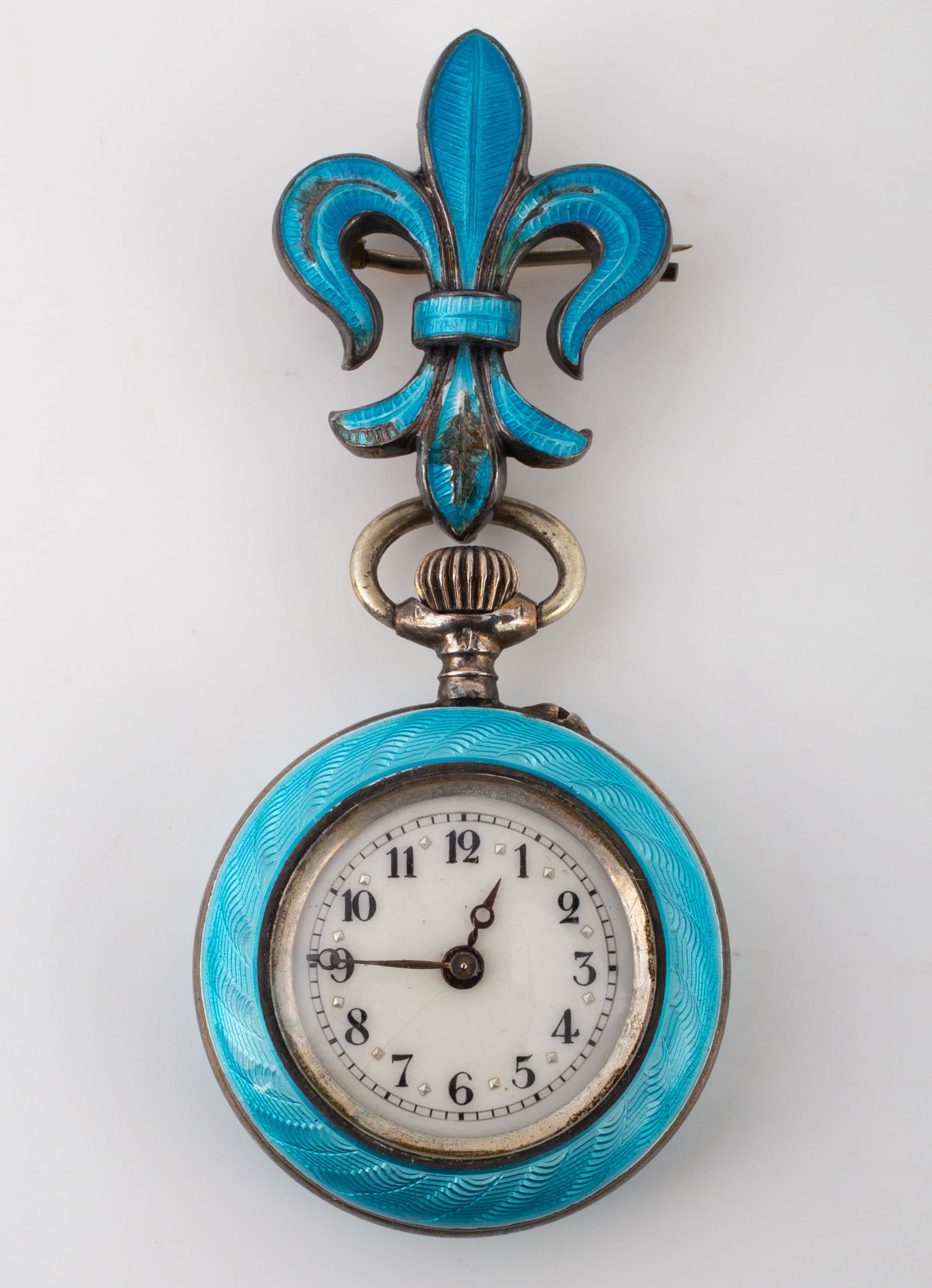 ENAMELED BROOCH WATCH: Unknown maker; silver tone with guilloche blue enamel; case with fleur de lis form brooch hanger; ticking; brooch hanger has a moderate amount of enamel wear and loss; L-2 1/2", G-VG