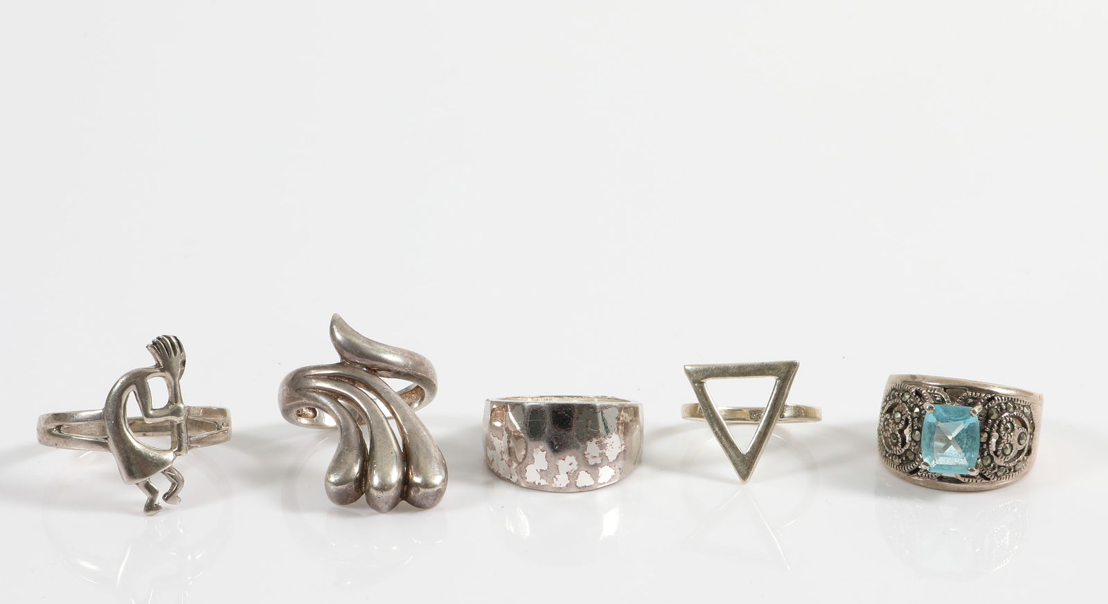 (5) STERLING RINGS: (1) hammered band, size 7.5, .36 ozt; (1) Kokopelli, size 13.5, .17 ozt; (1) triangle, size 5 3/4, .088 ozt; (1) abstract, size 7.25, .22 ozt; (1) two carat light blue rectangular stone, size 8.5, .26