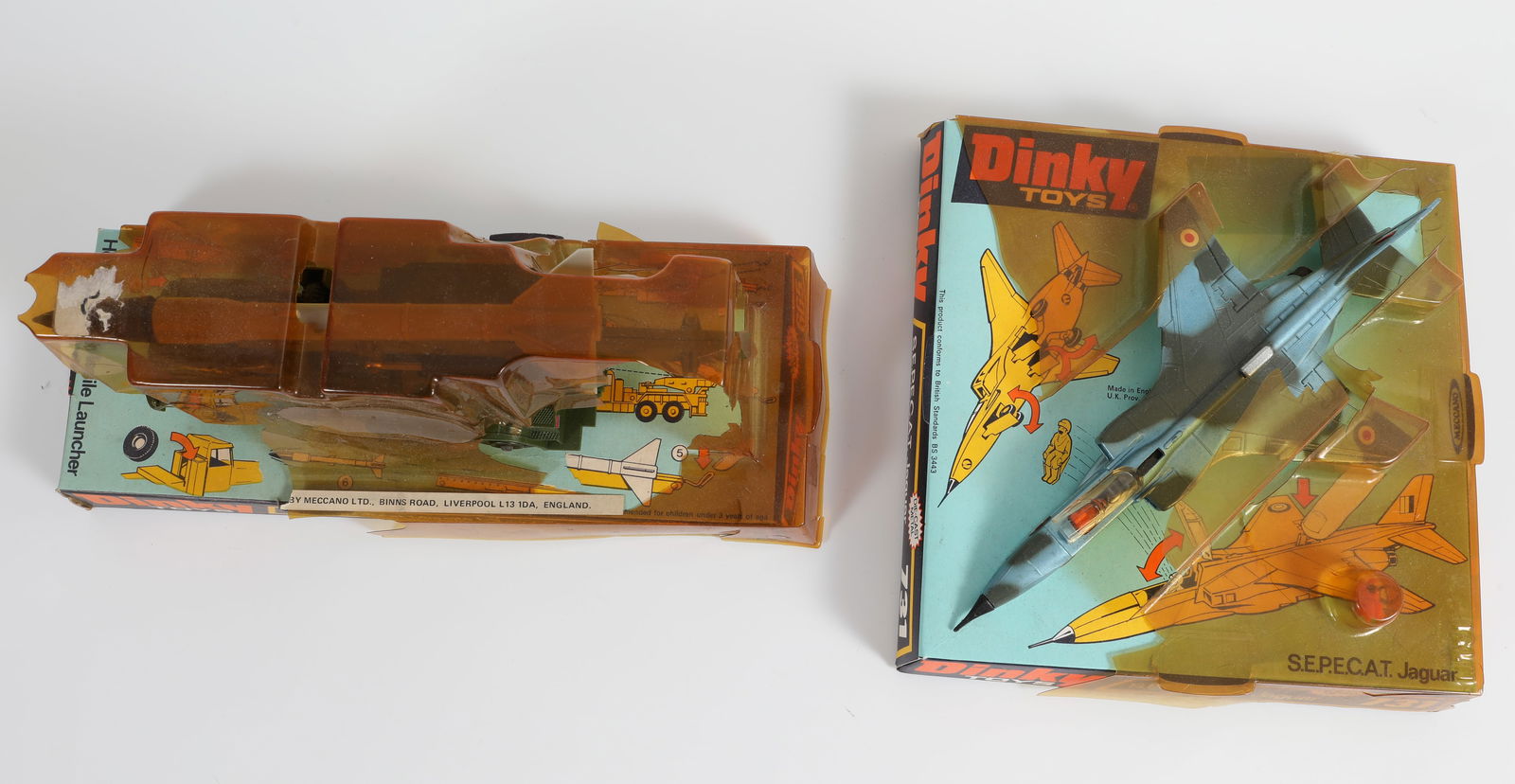 (2) DINKYS: S.E.P.E.C.A.T. JAGUAR & HONEST JOHN MISSILE LAUNCHER: Both with original packaging; both unplayed with; plastic coverings are darkened, with losses and breaks; litho cardboard bases are complete with edge wear, (1) S.E.P.E.C.A.T. Jaguar #731 fighter: ret