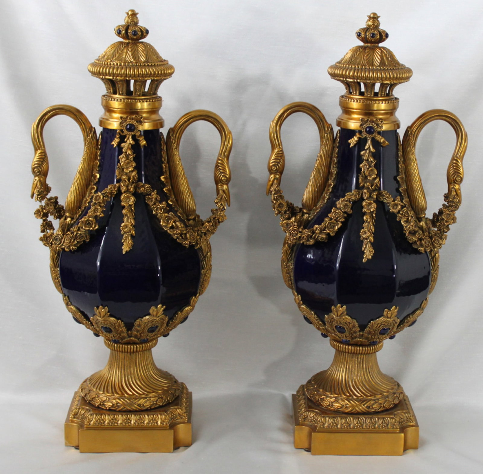 Pair of Bronze Mounted Blue Porcelain Lidded Urns, 20th Century: Pair of Bronze Mounted Blue Porcelain Lidded Urns, 20th Century A striking pair of decorative lidded urns, each crafted from deep cobalt blue porcelain and adorned with finely cast and gilt bronze mou