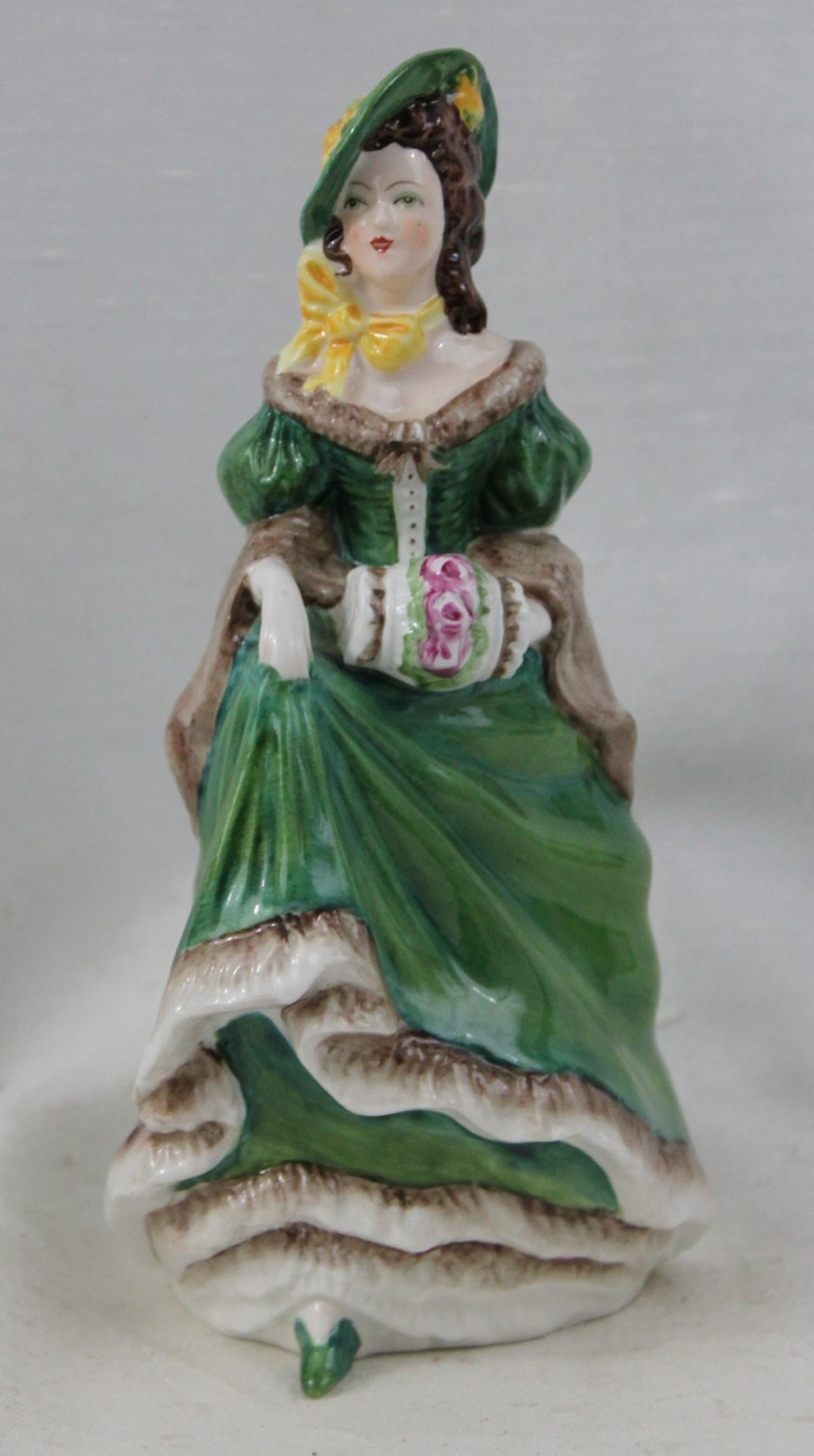 Coalport Porcelain Figurine "Judith Ann," England: Coalport Porcelain Figurine "Judith Ann," England A fine Coalport bone china figurine titled "Judith Ann," made in England. Depicting an elegant lady in a green gown with yellow accents and muff, wear
