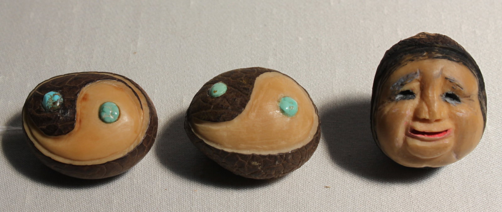 Three Carved Tagua Nut Ornaments with Yin-Yang & Mask Motifs: Three Carved Tagua Nut Ornaments with Yin-Yang & Mask Motifs Lot of three hand-carved tagua nuts (approx. 1.5 in. dia. each). Two are carved as yin-yang medallions, each inset with small