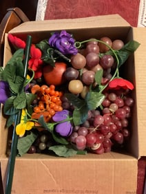 box full of fake fruit and flowers