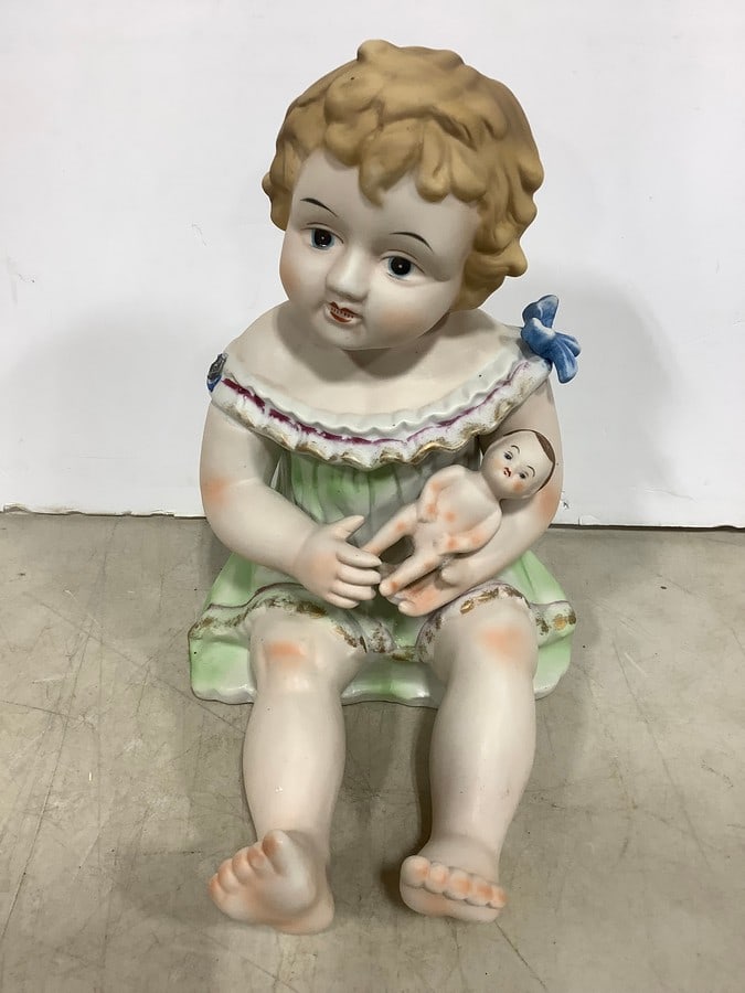 Porcelain Bisque Piano Baby Holding Doll Statue (12in Tall): Porcelain Bisque Piano Baby Holding Doll Statue (12in Tall)Is missing blue ribbon n right shoulder