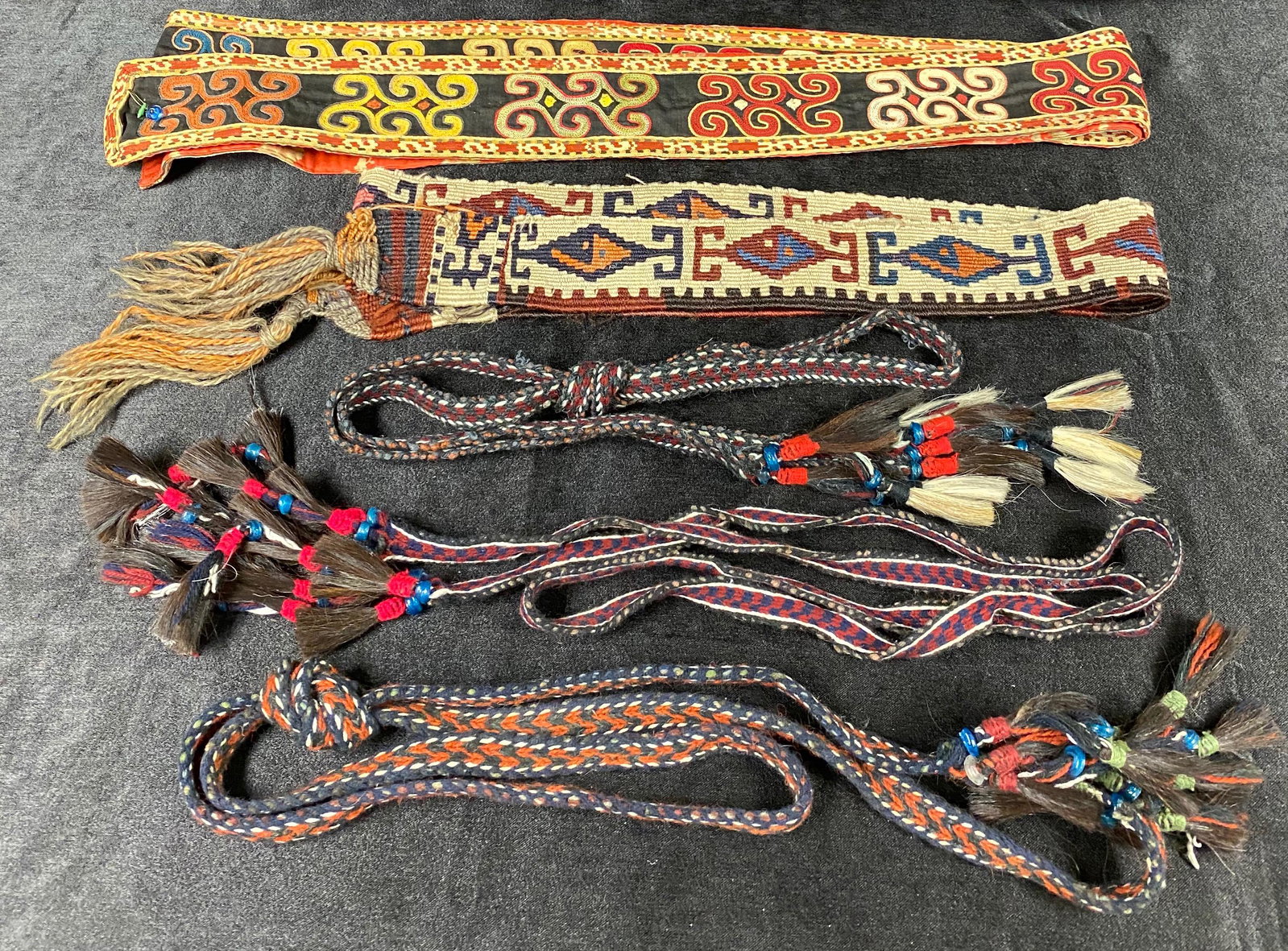 Uzbekistan | Lakai Sash & Belts | Tribal Designs: Uzbekistan Central Asia | Lakai Sash & Belts | Tribal Designs | Three Wool Belts w/Horse Hair Tassels| Measures 75-78" L 3/4 W | Sash with Red Floral Backing and All Seeing Eye Bead Measures 112 L x 3