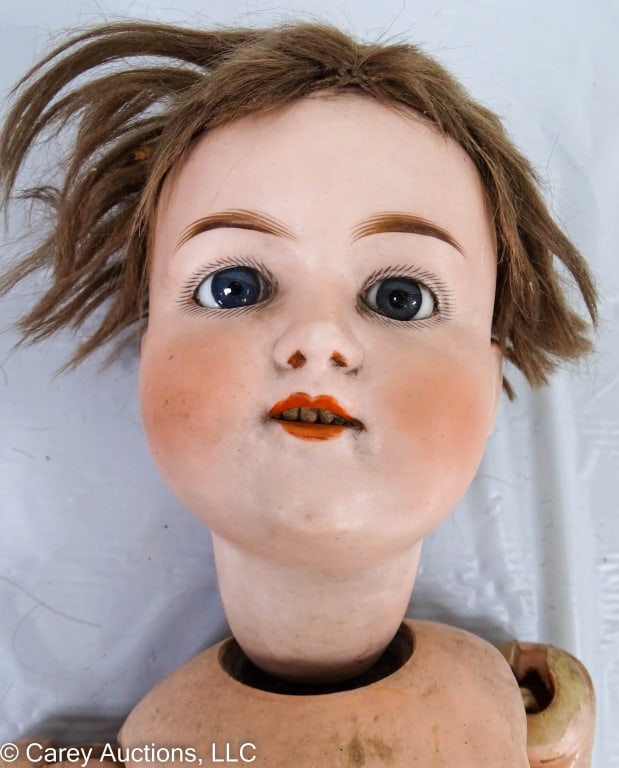 ARMAND MARSEILLE 21" DOLL: Bisque head with fixed glass eyes, open mouth with top teeth, mechanical moving head and legs, composition body, green dress. Back of neck is marked [M.H. 6 1/2] / Measures: 21" long / Condition: Atti