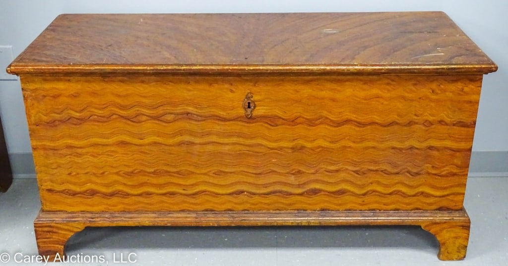 GRAIN PAINTED PINE DOVETAILED BLANKET CHEST: 6-board dovetailed grain painted blanket chest box. Sits on bracket feet. Inside has till and rat tail strap hinges. Missing lock. Writing on inside of lid is illegible / Measures: 25"H x 50.5"W x 20.