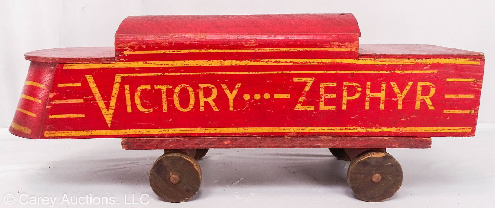 1920-30's VICTORY-ZEPHYR WOODEN TRAIN: A wooden locomotive from the early 20th Century, painted red with yellow detailing, marked [Victory...-Zephyr] in an art deco design // Measures: 9.5"H x 25"W x 6.75"D // Condition: Mis