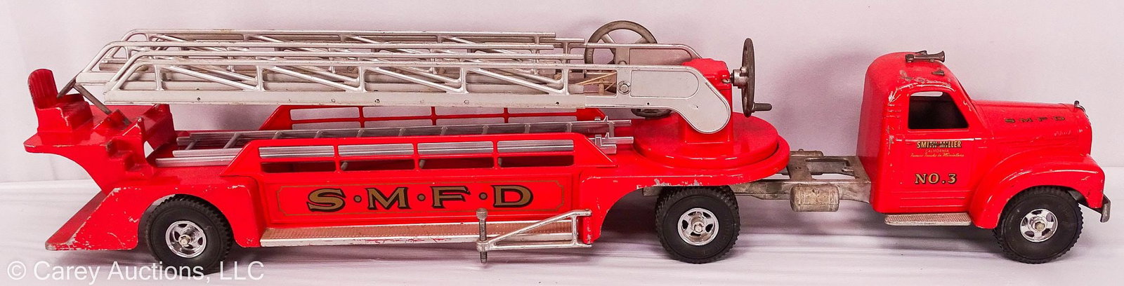 SMITH-MILLER AERIAL LADDER FIRE TRUCK No 3: An original Smith-Miller Fire Department Aerial Ladder Fire truck, with trailer, marked [SMFD] for Santa Monica Fire Department // Measures: 8"H x 44"L x 6"W // Condition: Minor paint c