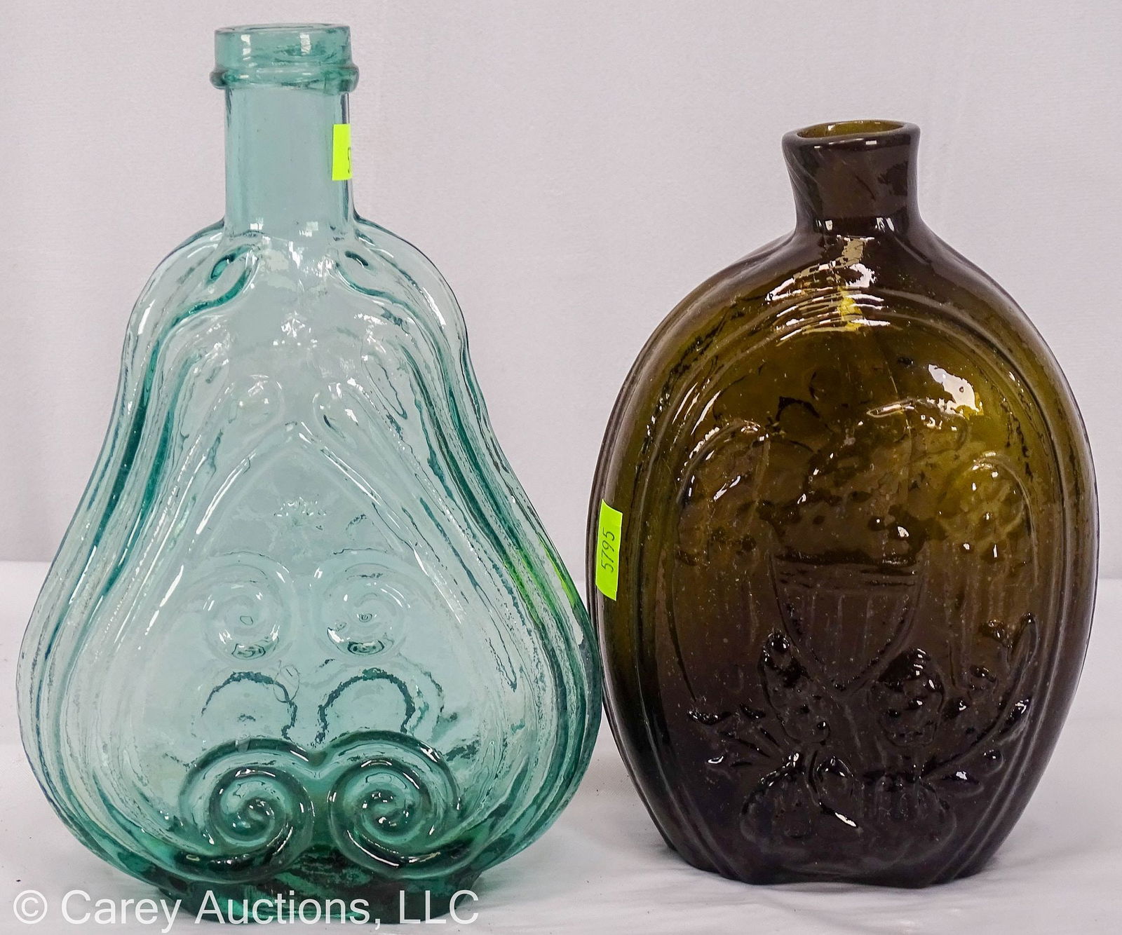 TWO HISTORICAL GLASS WHISKEY FLASKS 19TH CENTURY: Includes [1] 1850's aquamarine pint scroll flask with iron pontil. Nice color, some bubbles and marks in glass. // Measurements: 7.5" H X 5" W X 2"D // Condition: Small imperfection
