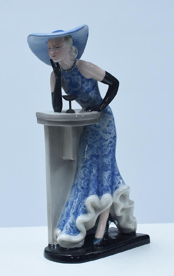 Goldscheider figure of Art Deco woman in blue hat: Goldscheider figure of Art Deco woman in blue hat, blue patterned dress, and black gloves, with martini glass on the bar. Marked “Goldscheider Wien, made in Germany, impressed 7509-279-19, ca.19