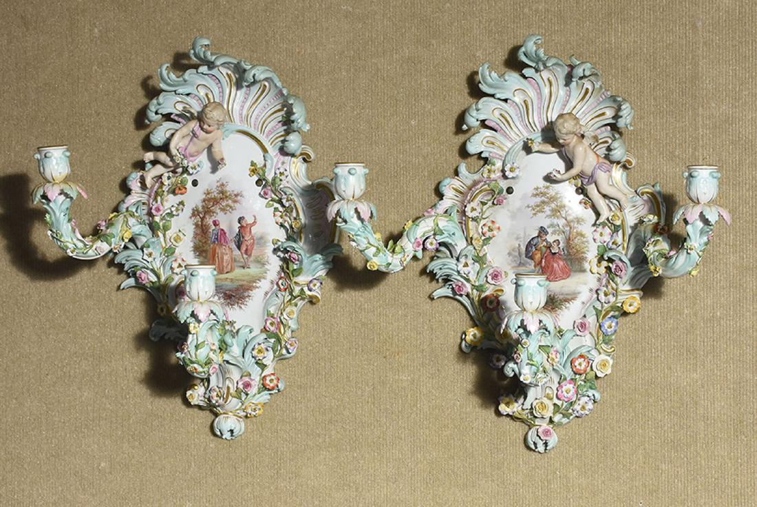 Pair of Rococo style Meissen wall sconces: Pair of Rococo style Meissen wall sconces, with center plaques painted with courting scenes, one missing arm, 18.5”H x 17”W with arms