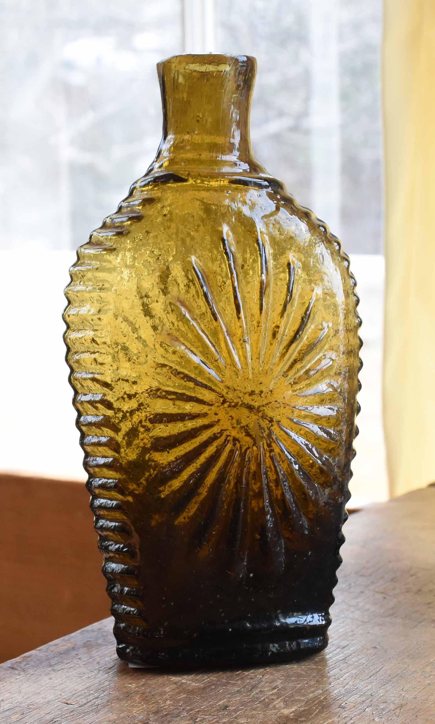 Early Olive Glass Flask, Sunburst: Early olive/amber glass flask with sunburst design, unmarked Keene, with pontil mark. 6.5”H x 3.25”W.