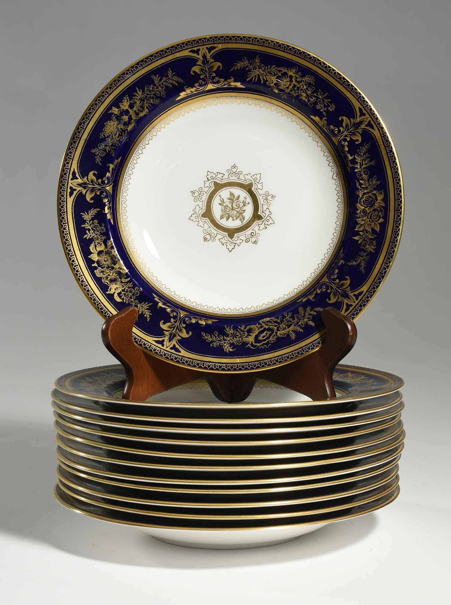 Set of Twelve Wedgwood Soup Bowls: Set of Wedgwood shallow soup bowls with gold and cobalt floral borders, with gilded center decoration, signed on bottom “Wedgwood England” with vase, one unsigned. 10”Dia. 