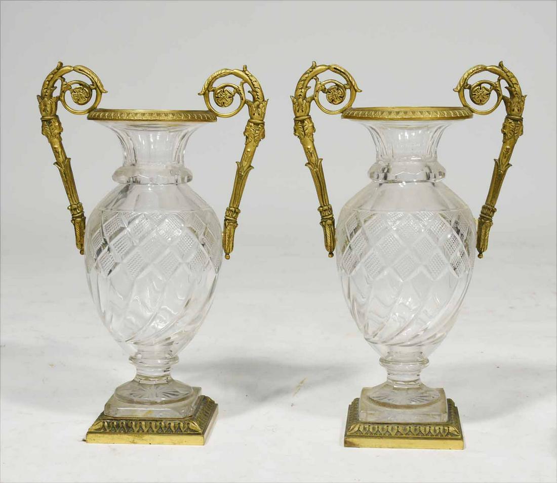 Pair of Bacarrat Glass Urns: Pair of cut glass urns with doré bronze mounts, possibly Baccarat, with spiral handles and square base, 11”H x 7”W.