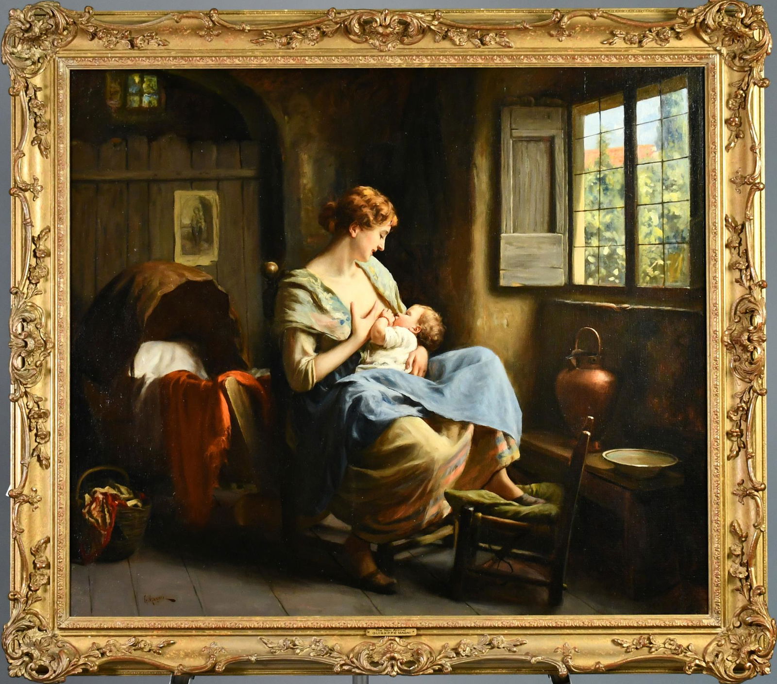 GIUSEPPE MAGNI O/C 'THE NEW ARRIVAL'.: A large oil on canvas of a woman sitting in front of a window gazing at her nursing infant who wears a red coral bracelet, in a European interior room, signed lower left G. Magni with a plaque on the