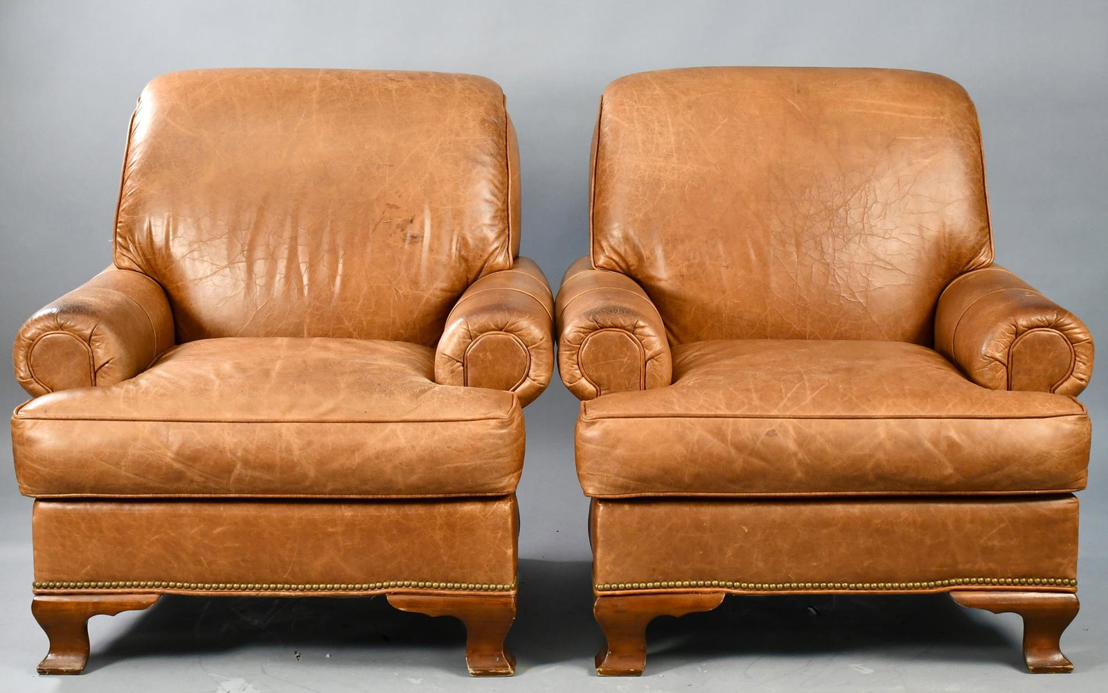 PAIR OF SOUTHWOOD LEATHER CLUB CHAIRS.: Contemporary leather club chairs by Southwood with slip seats and brass tack around bottom apron, on mahogany bracket feet. 37”H x 34”W x 17”seat height.