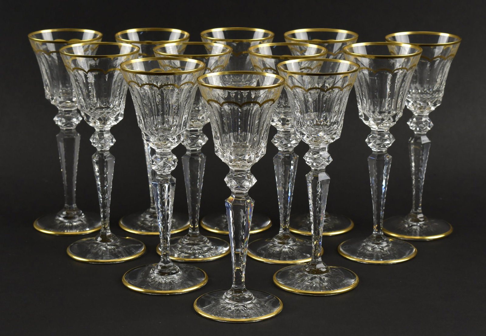 SET OF 12 SAINT LOUIS 'EXCELLENCE' WHITE WINE GLASSES: Cut crystal with gilt rims and scalloped gilt banding. All with St. Louis marks to bases. 8”H x 3”dia. .