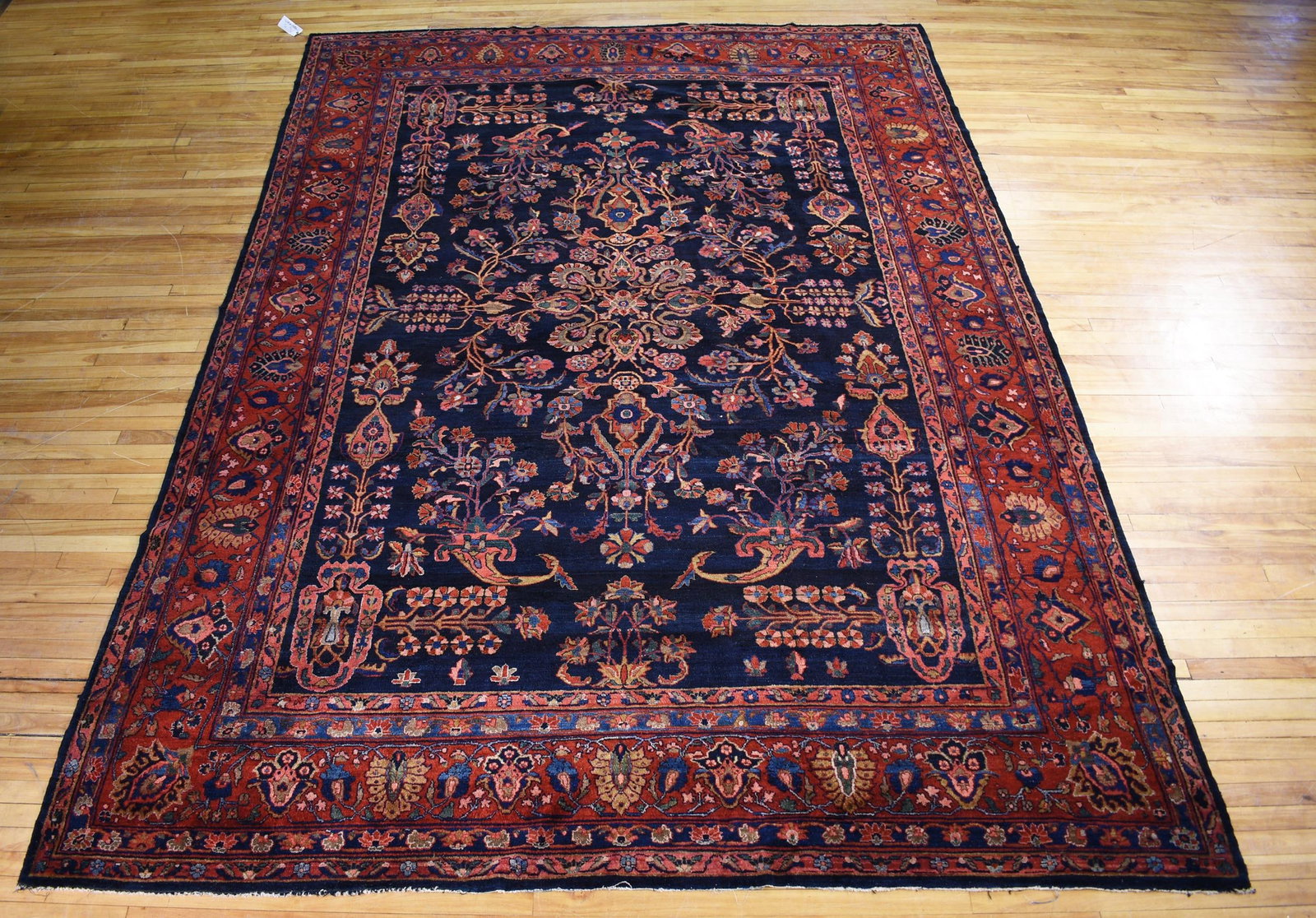 ANTIQUE ORIENTAL SAROUK ROOM SIZE RUG.: An unusual antique Oriental Sarouk room size rug, with a cobalt central field, flowering cornucopia and central floral medallion, surrounded by a rich red border. 8’10” x 12’7”