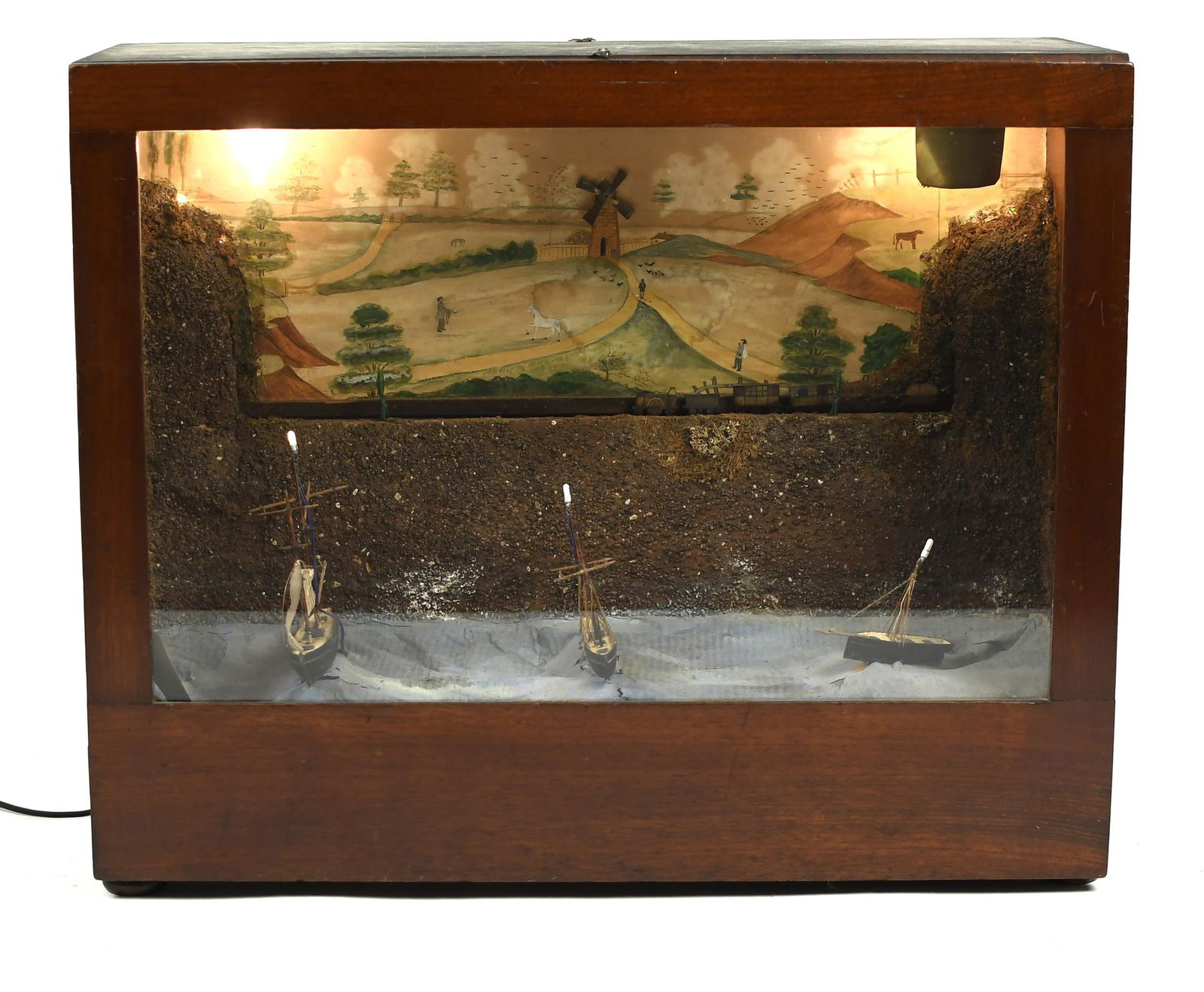 EARLY 20TH C. MECHANICAL DIORAMA, TRAIN & SHIPS.: An exceptional mechanical diorama with an illuminated landscape depicting a train which moves from side to side, over three boats that rock back and forth in stormy ocean waters, all contained in a do