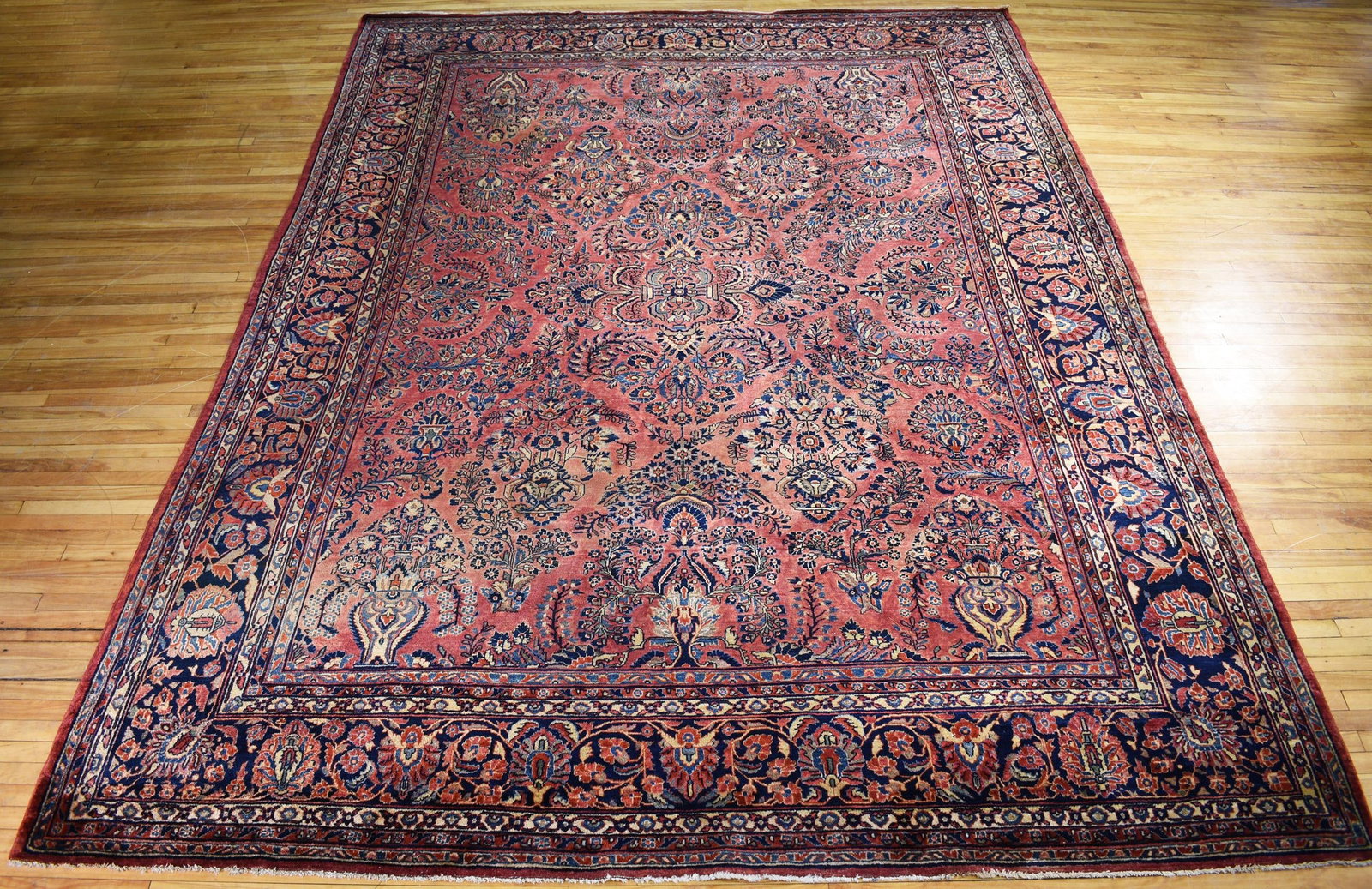 ANTIQUE ORIENTAL SAROUK ROOM SIZE RUG.: A classic antique Oriental room size Sarouk rug, with repeating flowering urns in a central field with a complimenting border, 10’2” x 13’10”.
