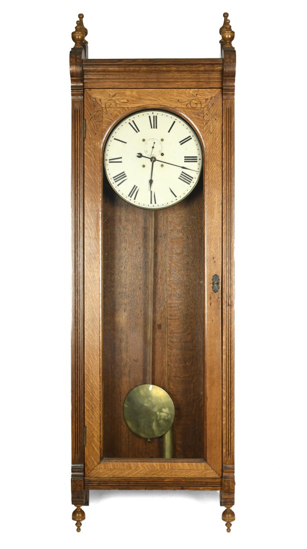 ANTIQUE SETH THOMAS NO. 17 REGULATOR CLOCK.: A large ca. 1900 Seth Thomas regulator wall clock, finial top with carved door and styles, 14” dial, with single weight and pendulum, overall 72”H x 23”W x 10”D.