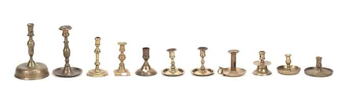 ELEVEN ANTIQUE BRASS CANDLESTICKS.