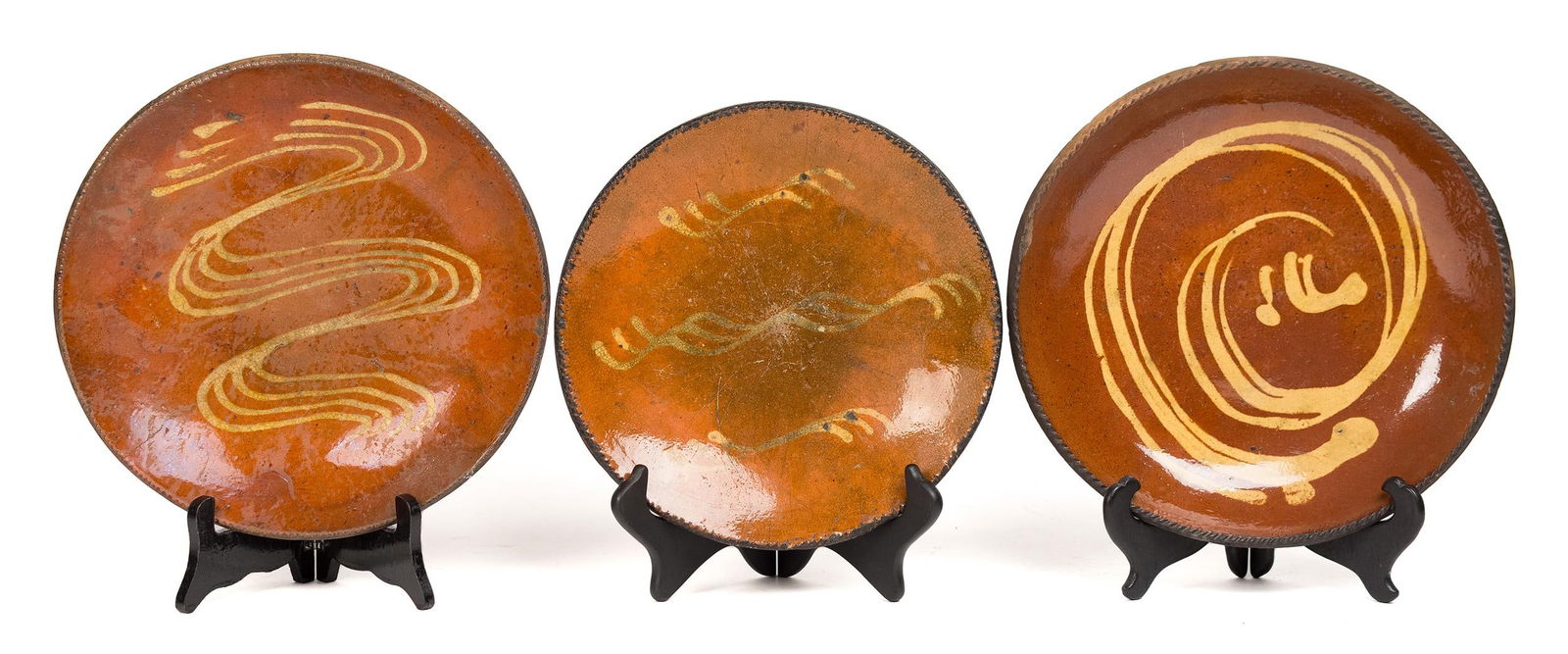 THREE 19TH C. PA SLIP DECORATED REDWARE PLATES.: Three mid 19th C. Pennsylvania yellow slip decorated redware plates, with scroll designs. 10”/11” dia. .