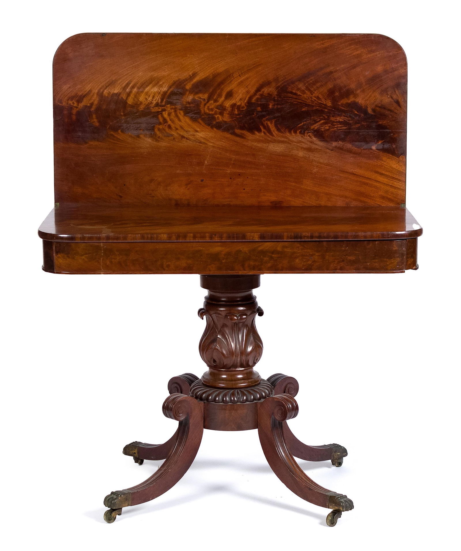 19TH C. CLASSICAL DUNCAN PHYFE CARD TABLE.: A mid-19th C. Duncan Phyfe card table, with a single board crotch mahogany lift top on a well carved acanthus leaf pedestal, terminating in carved legs with paw foot brass casters, 28.5”H x 36&#