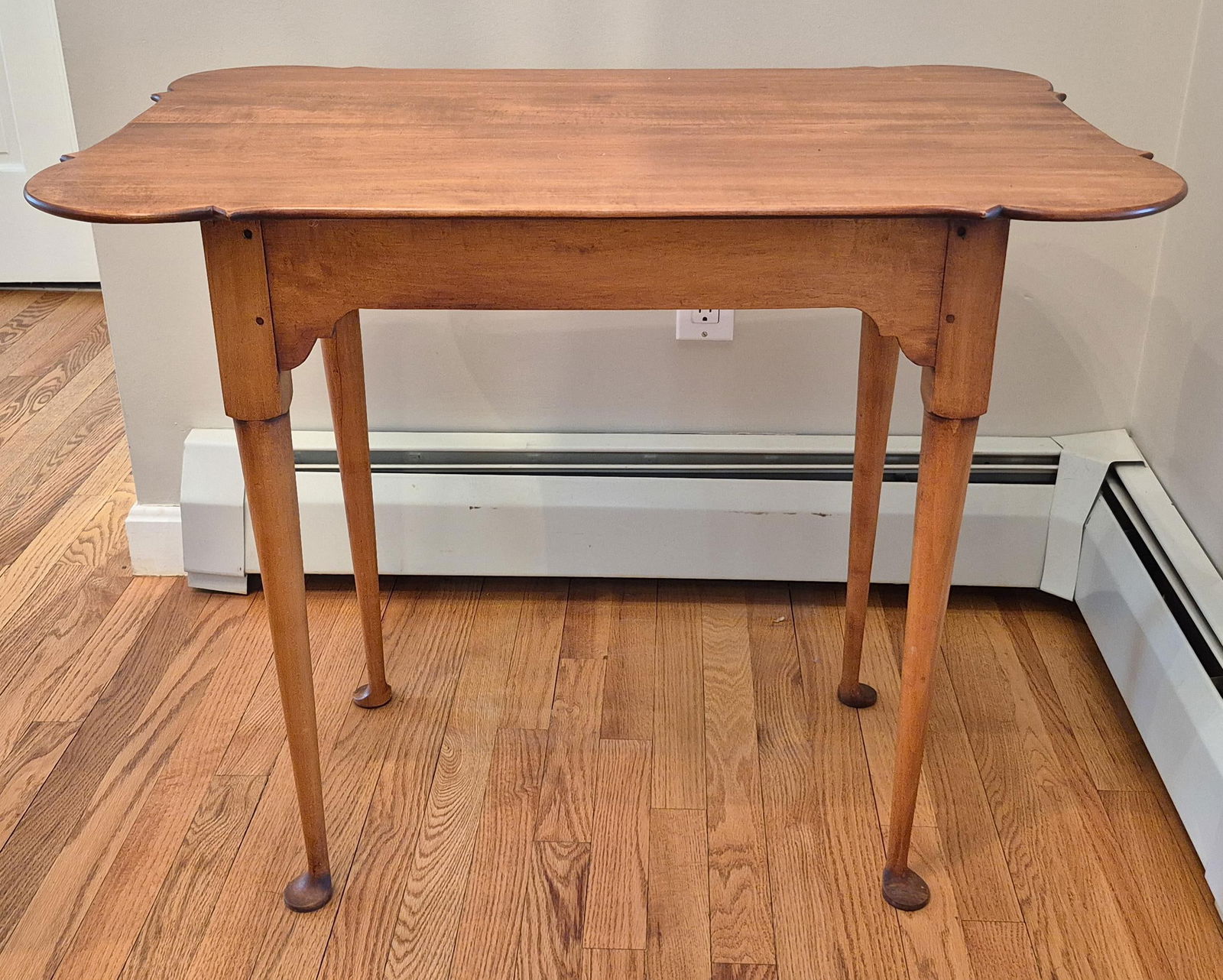 ELDRED WHEELER TIGER MAPLE TEA TABLE.: An Eldred Wheeler labeled, tiger maple Queen Anne style tea table with a porringer shaped top on cabriole legs. 27.5”H x 33”W x 22”D.