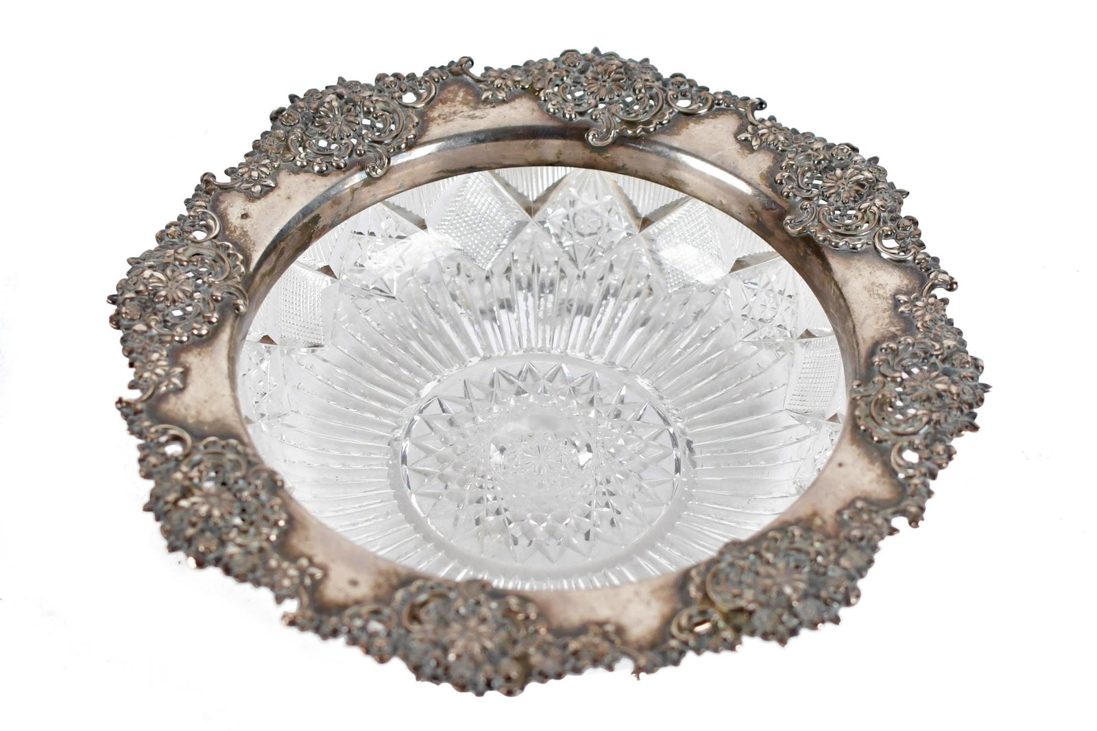 TIFFANY & CO. STERLING MOUNTED CUT GLASS BOWL.: A Tiffany & Co. sterling mounted low cut glass bowl, with a wide sterling rim decorated with chrysanthemums, buttercups and roses, marked Tiffany & Co. Cut glass bowl in rayed hob star, notched prism,